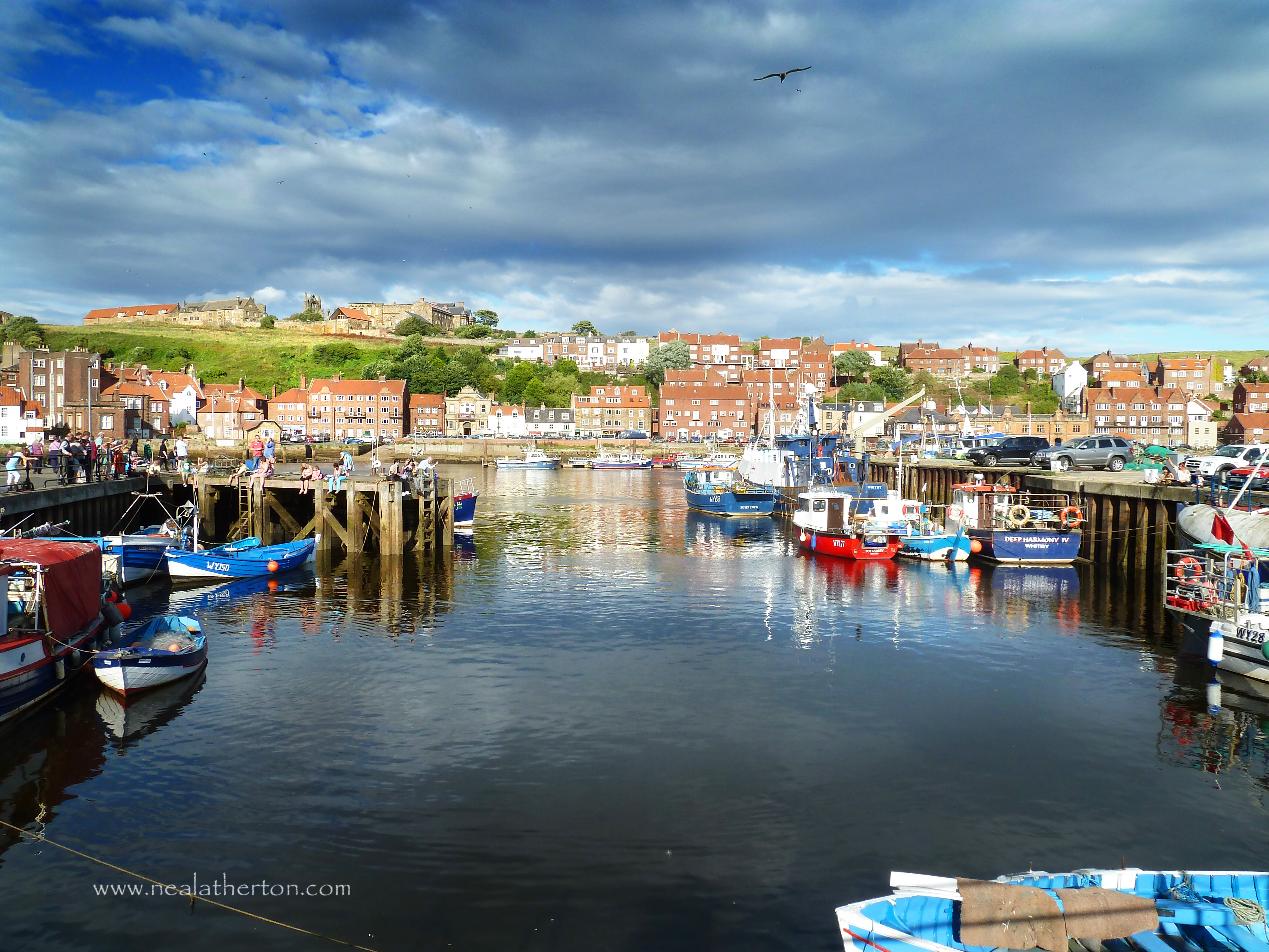 Alt="Photo of Whitby harbour and church and abbey ruins"