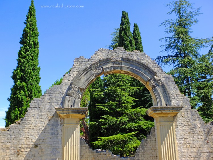 An almost complete stone Roman arch in the ancient town of Vaison la Roman in Provence with blue sky and trees
