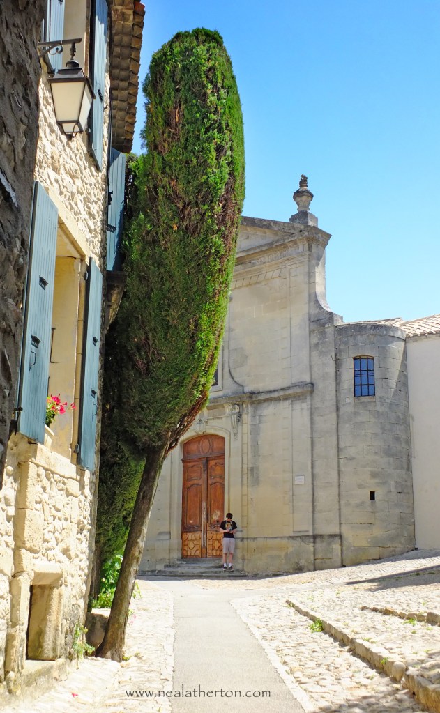 A man stands by the church door in the old town of Vaison in Provence France in French travel guide books