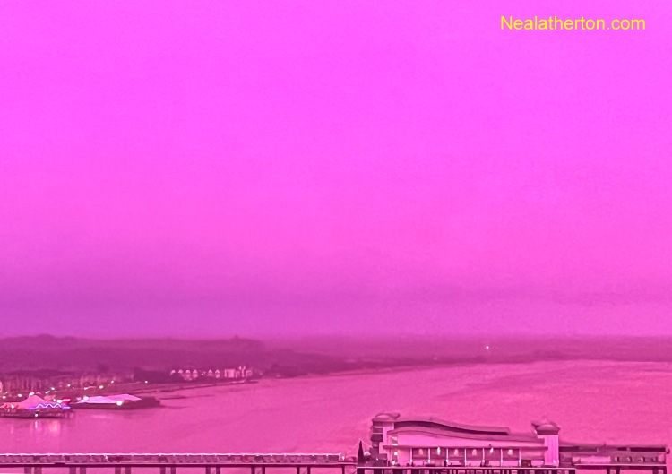 Weston Super Mare Somerset England Grand Pier in heavy rain with a pink sky looking over the beach
