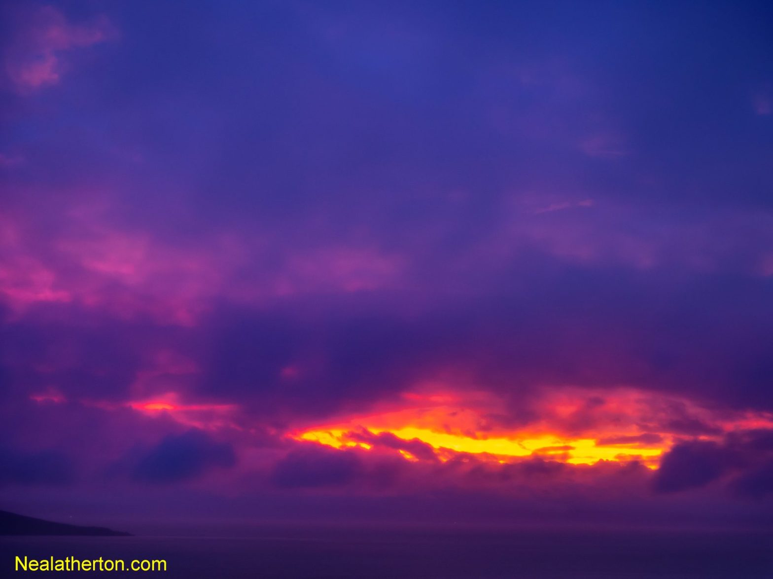 looking over the Bristol Channel to North Devon England we see fiery light after sunset breaking through some stormy clouds