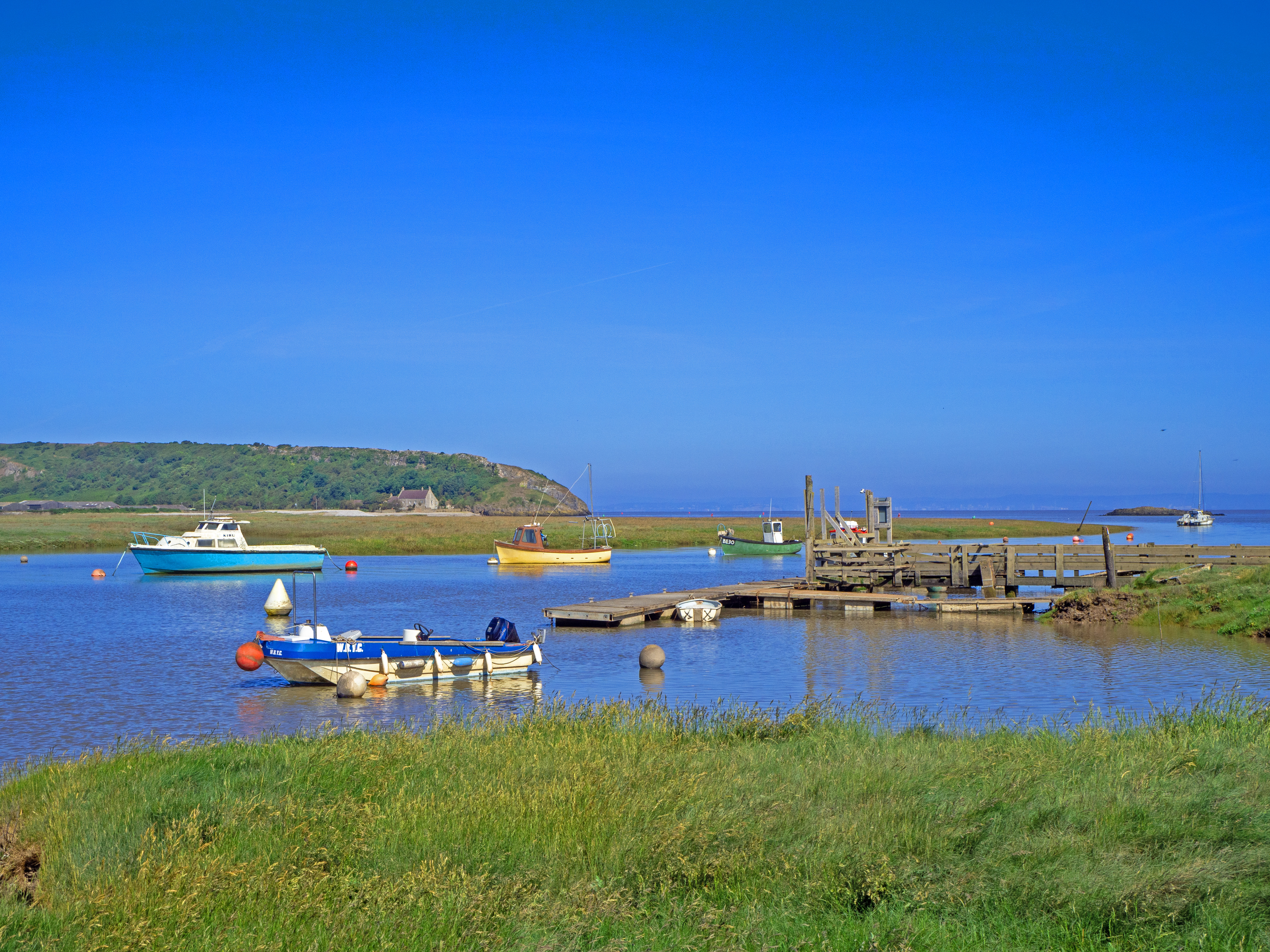 four boats and yacht on high water river Axe estuary somerset Brean down with deep blue summer sky