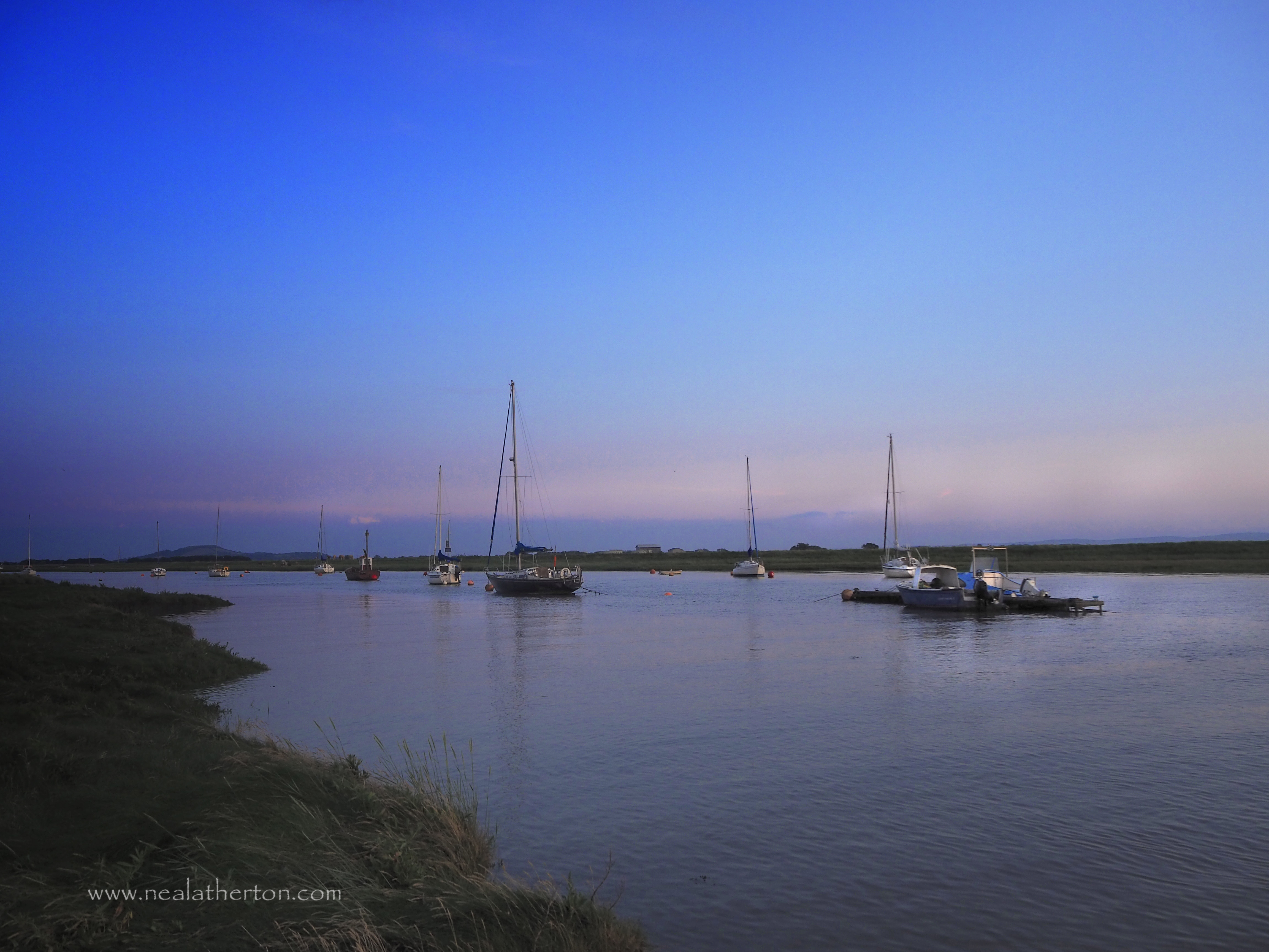 Calm scene at dusk on a high tide at Uphill Somerset with hazy sky and calm river
