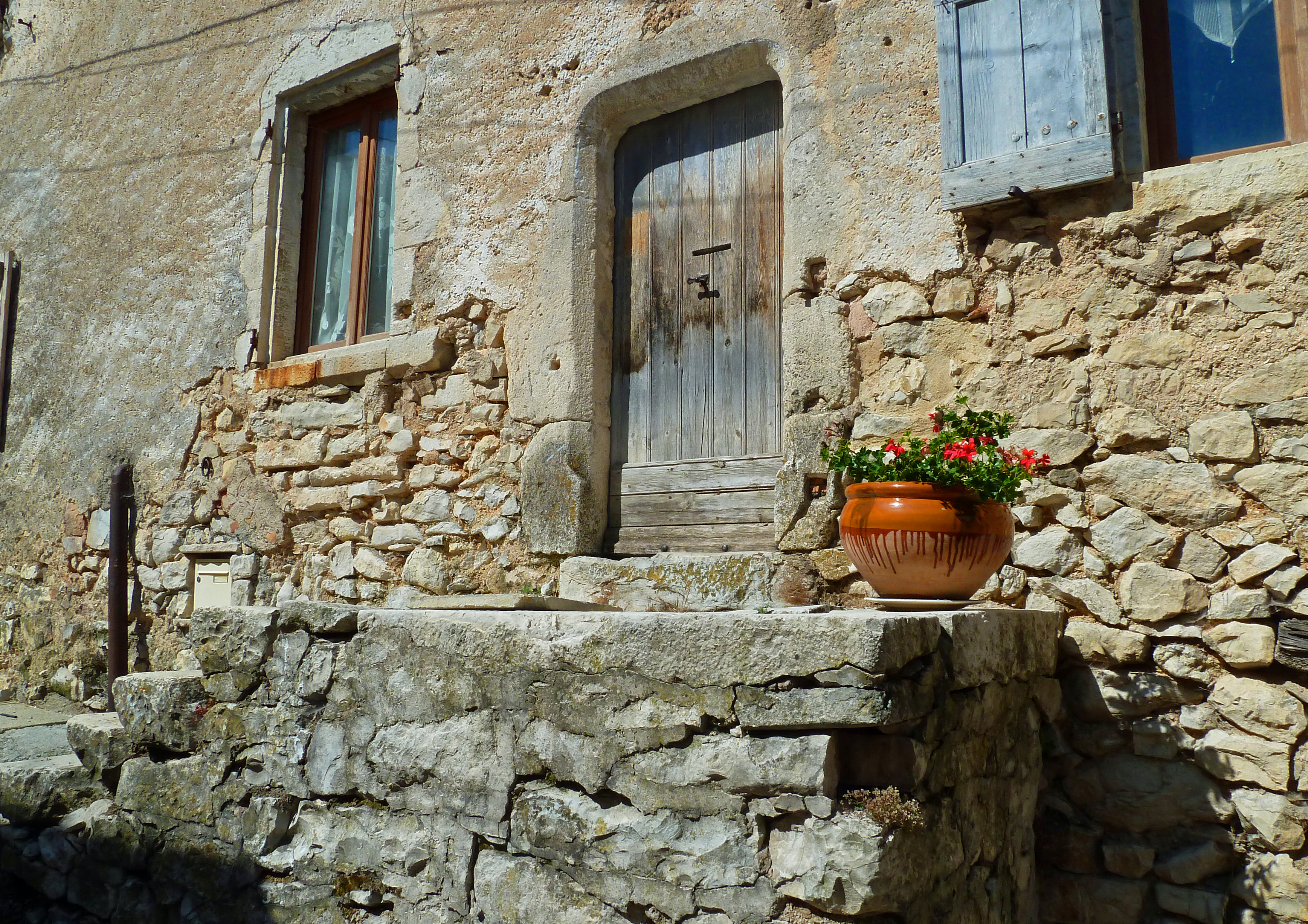 Flower pots on ancient steps in front of old building and door in Banon Provence France
