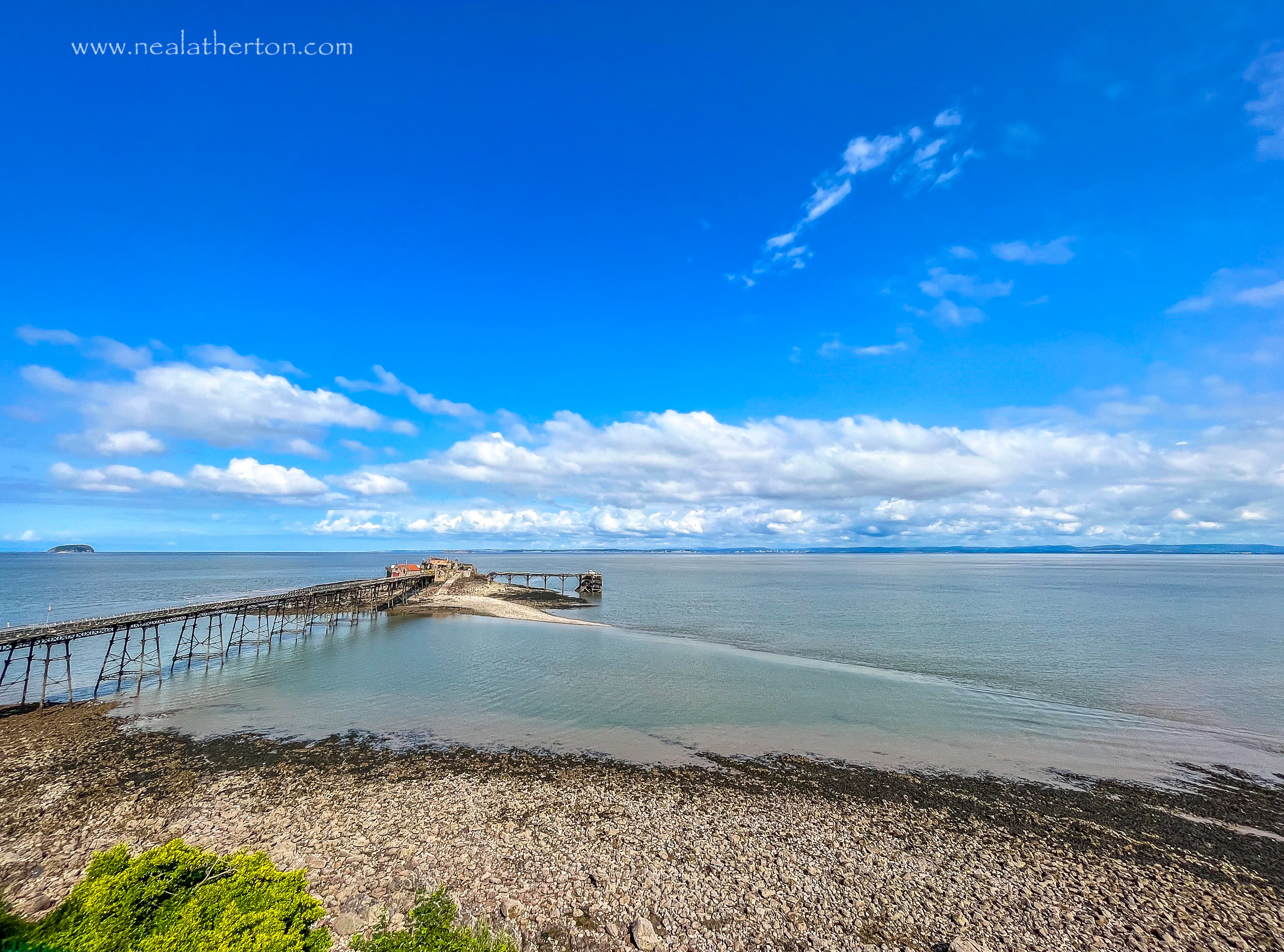 Pebble beach in front of the old pier in Bristol Channel with Wales in the distance