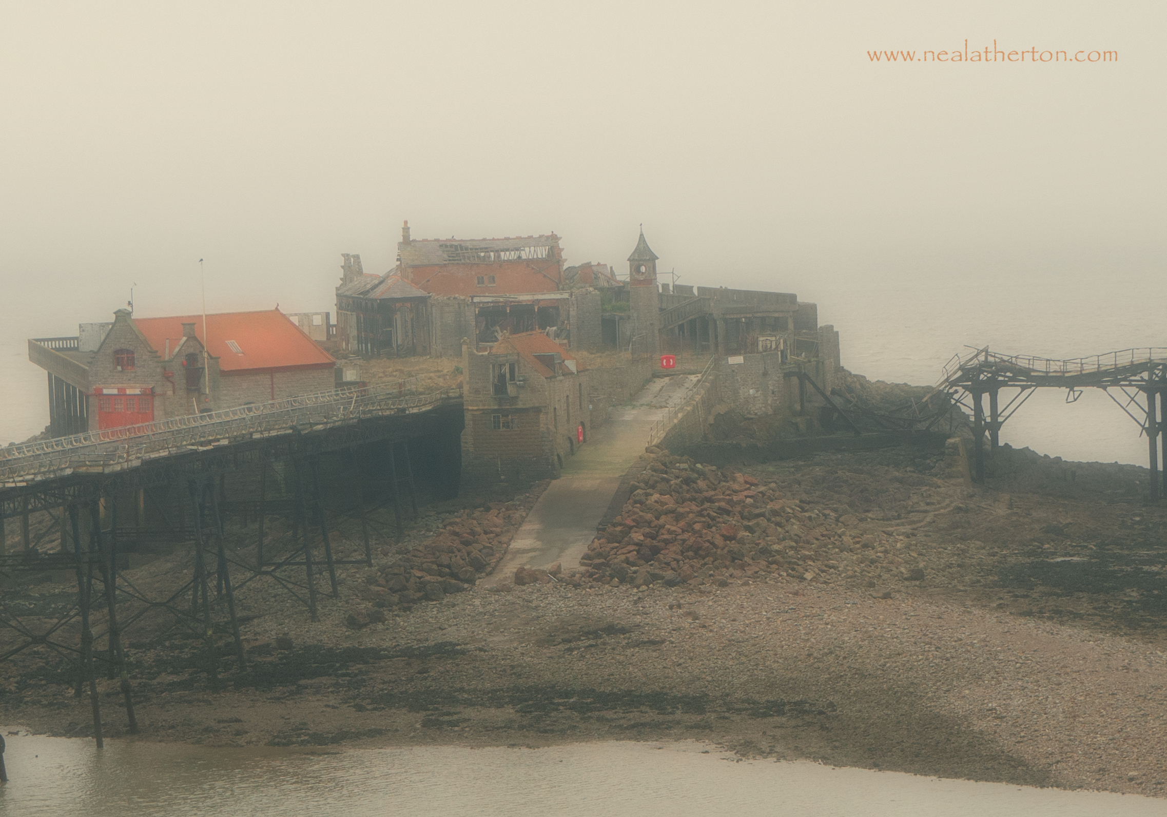 grey mist over pier with low tide on the bay