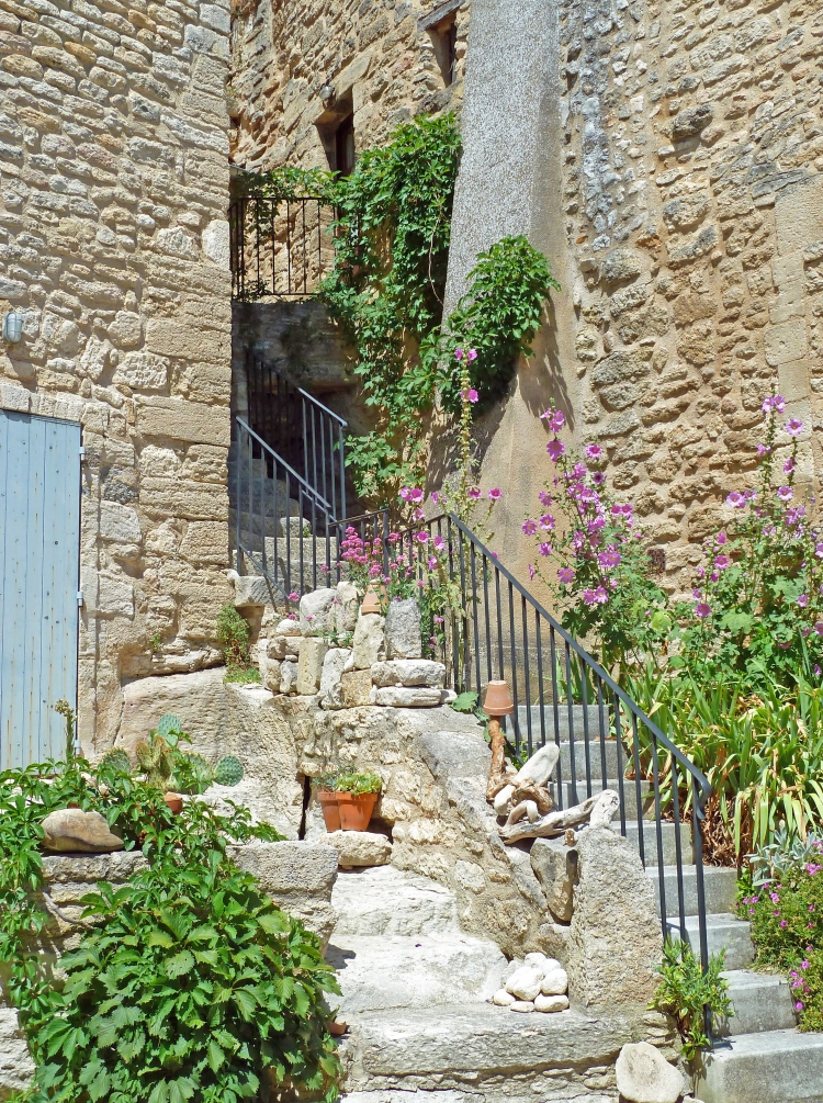 steps lead up to houses with green foliage and plant in ancient town in France