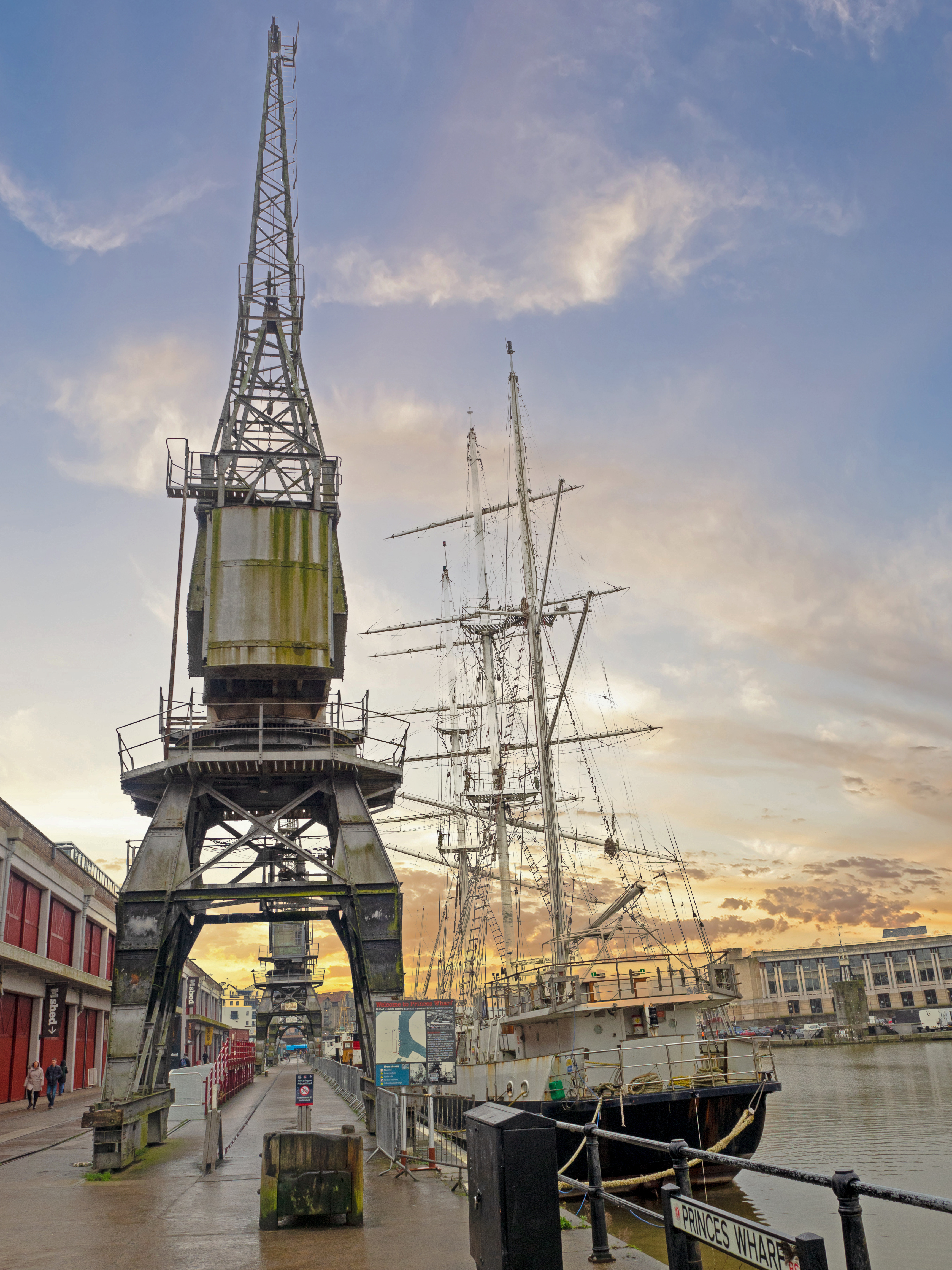 crane at docxks with boat and warehouse buildings near river