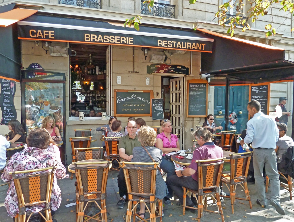 tables and chairs with people drinking at bistro with waiter