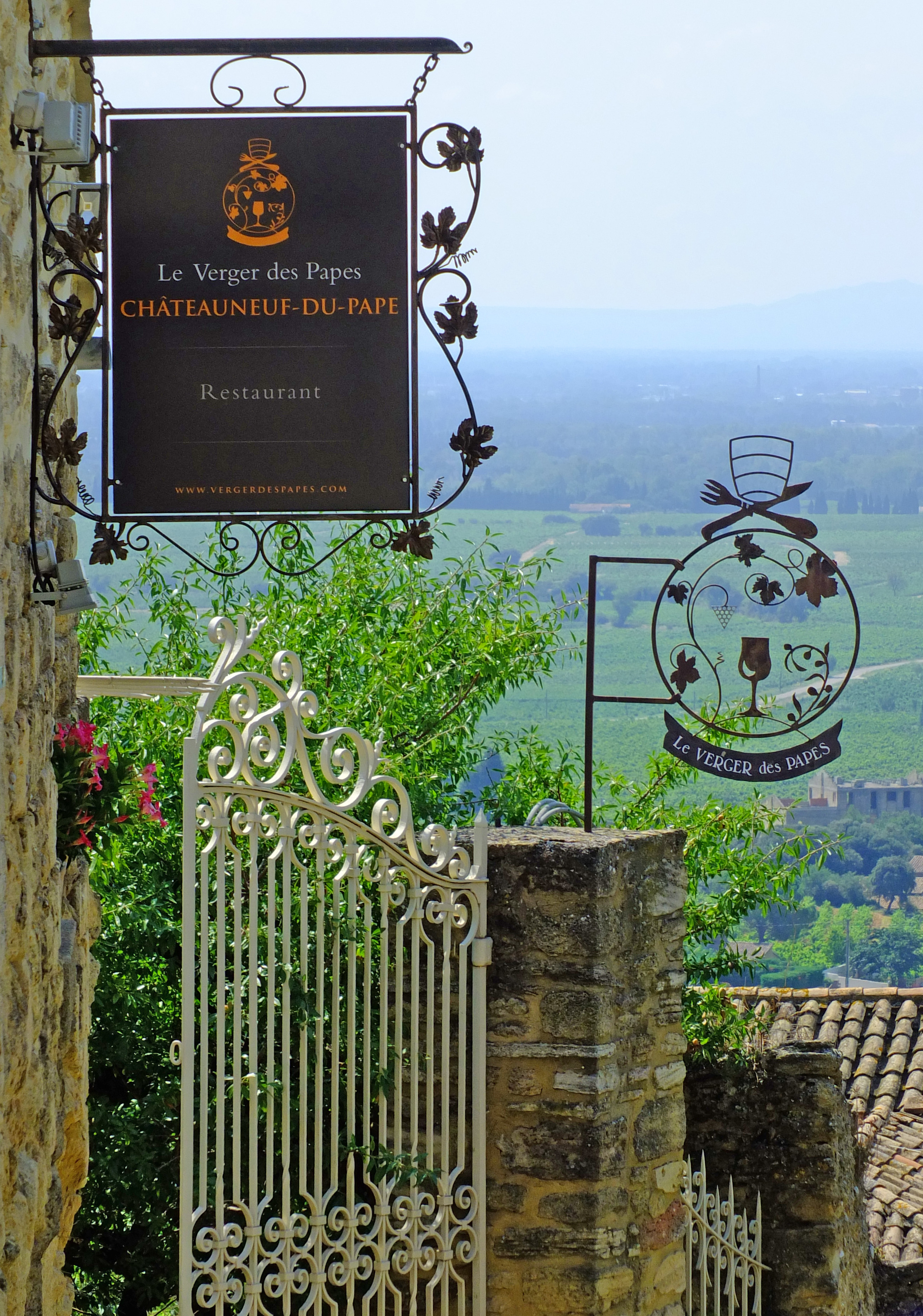 restaurant signs and metal gate in wall with valley below and mountains