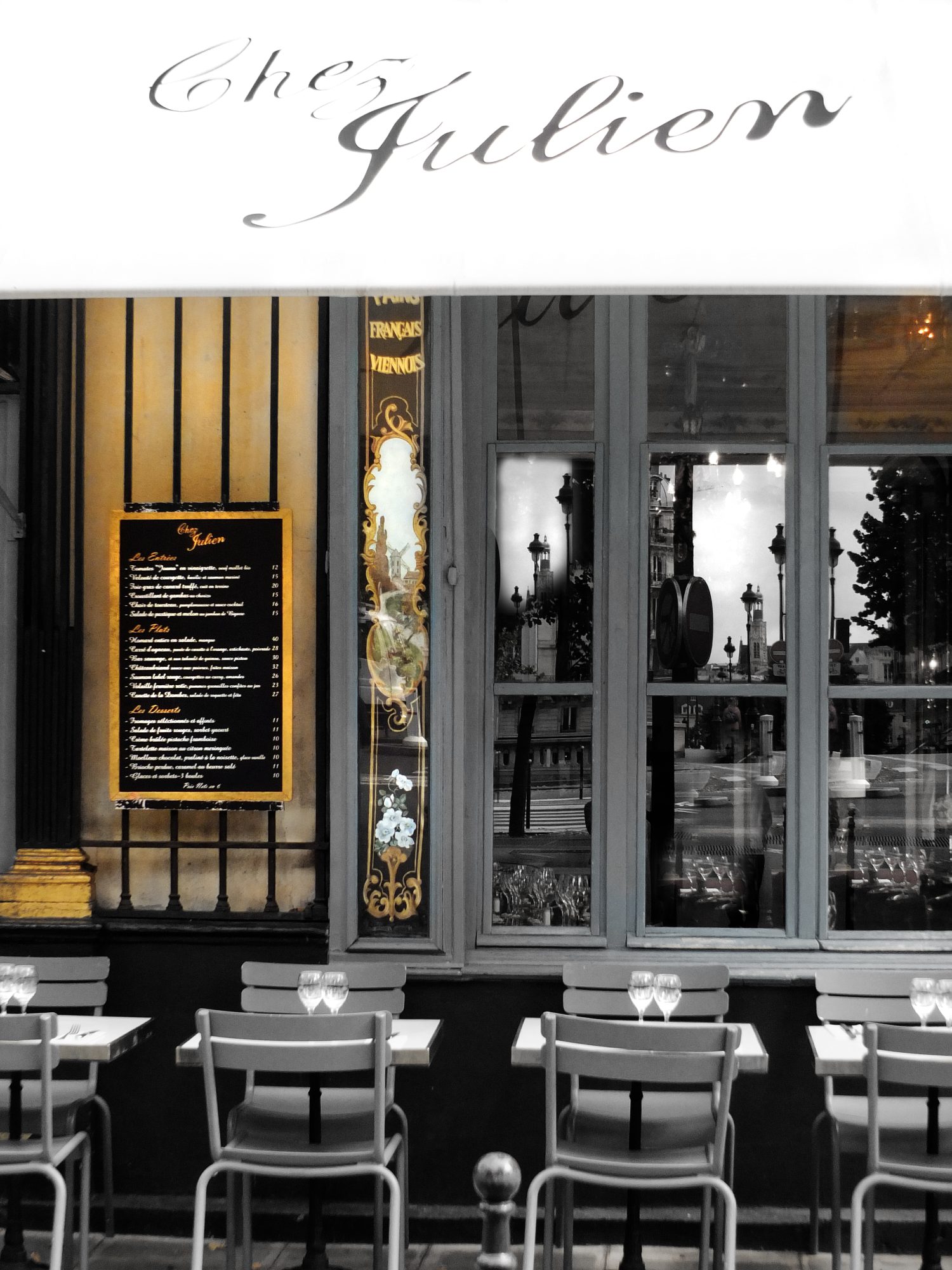 table and chairs in from of bistro window with menu and glass mirror