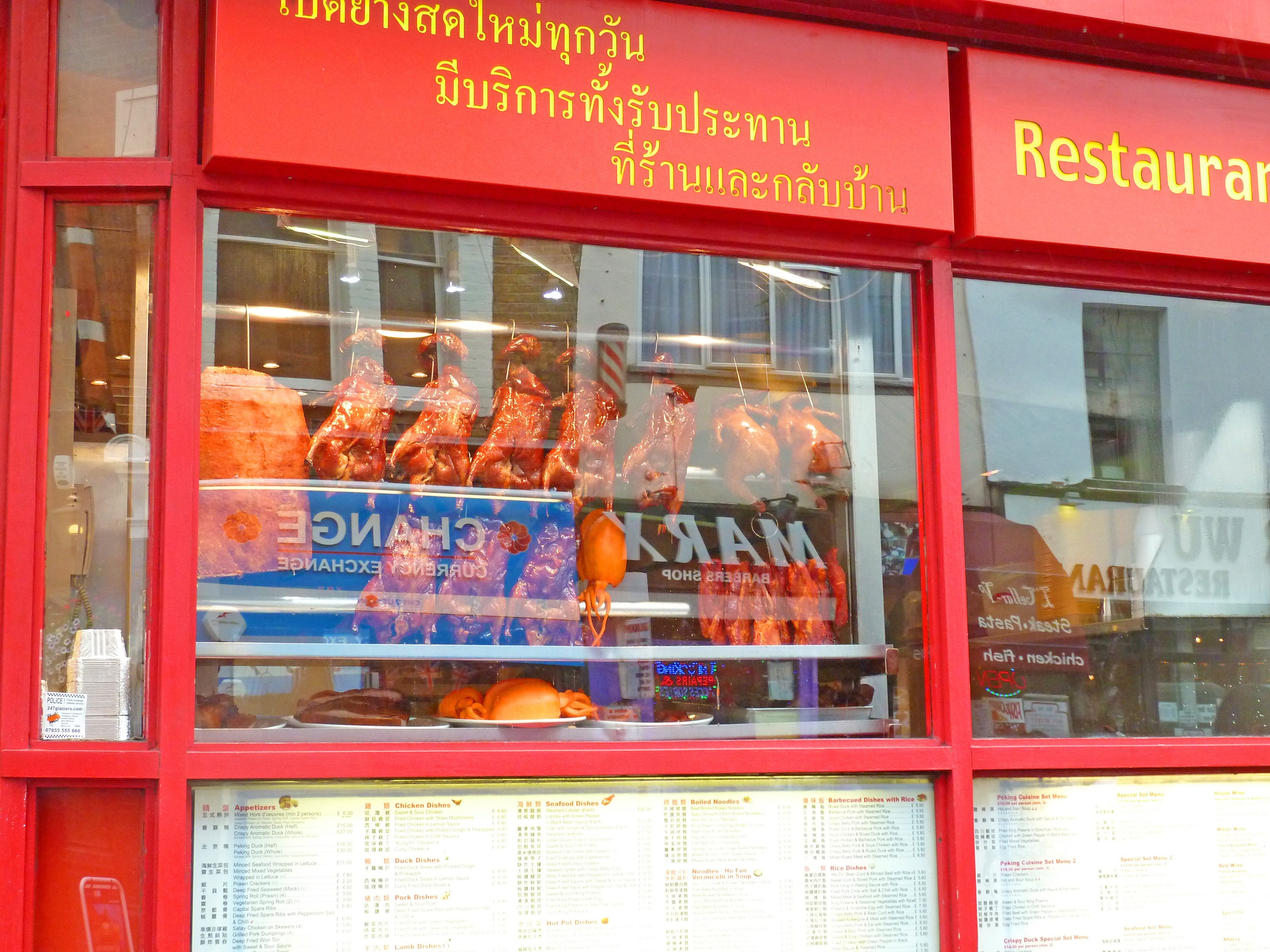 red restaurant front with yellow signage and cooked ducks in window
