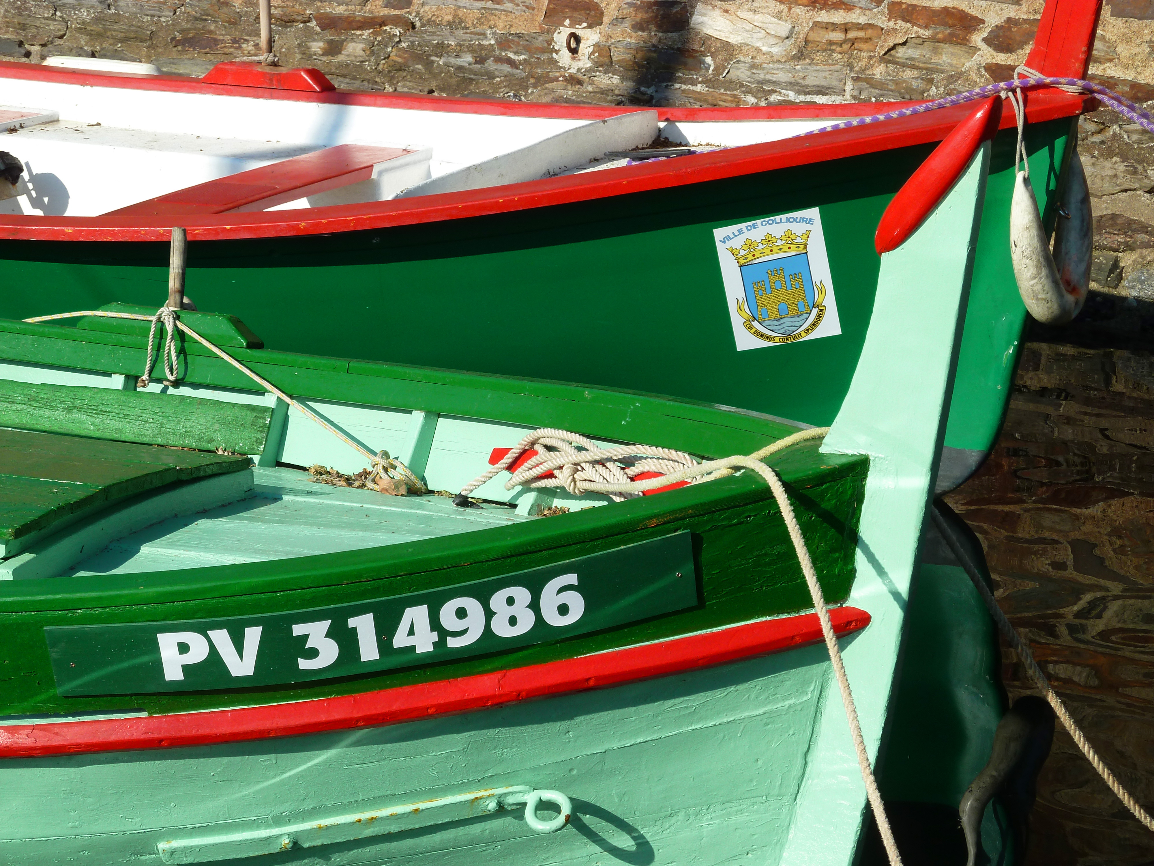 Brightly painted fishing boats in a harbour with wall