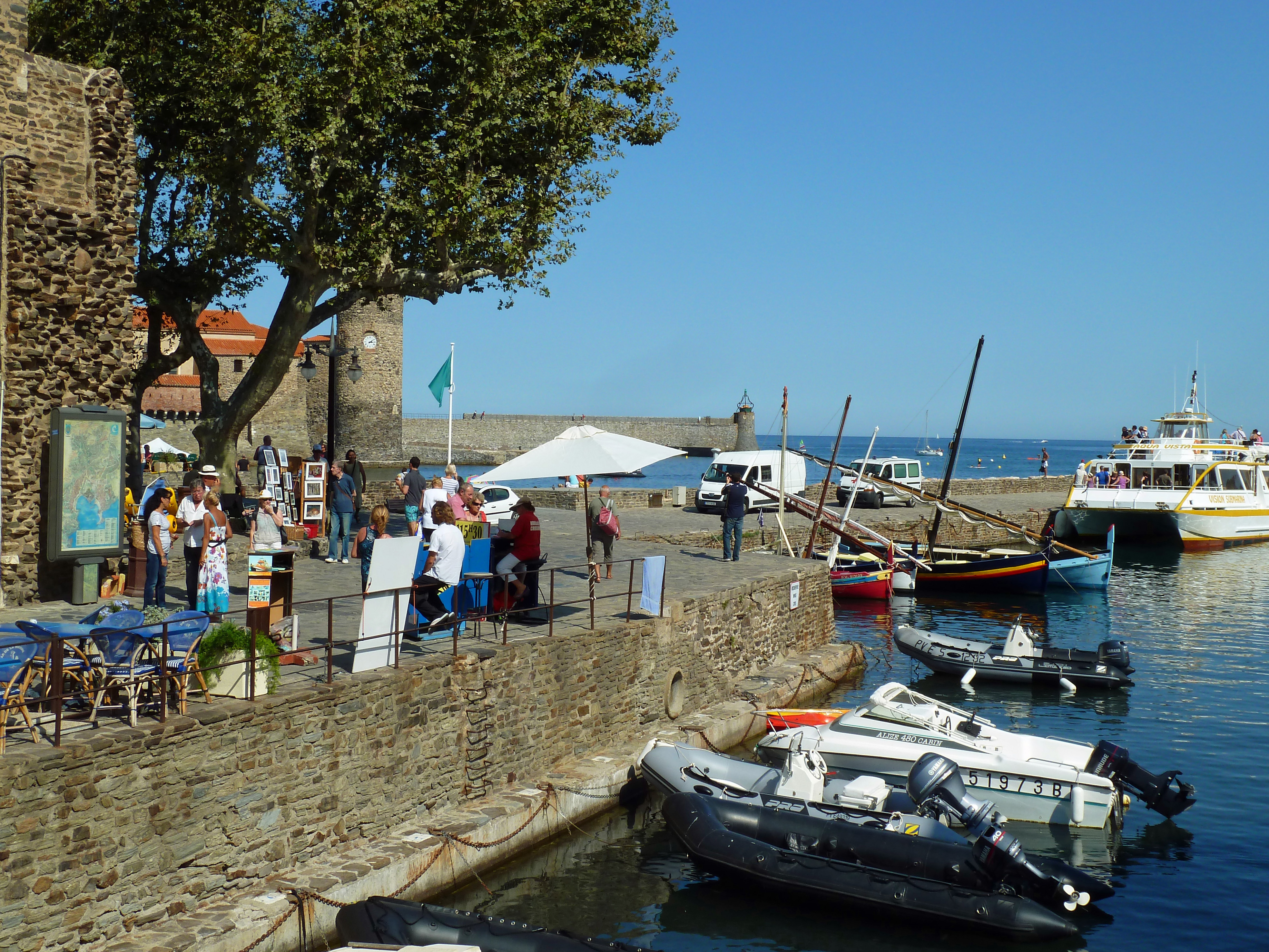 boats in harbour with harbour wall and church with artists