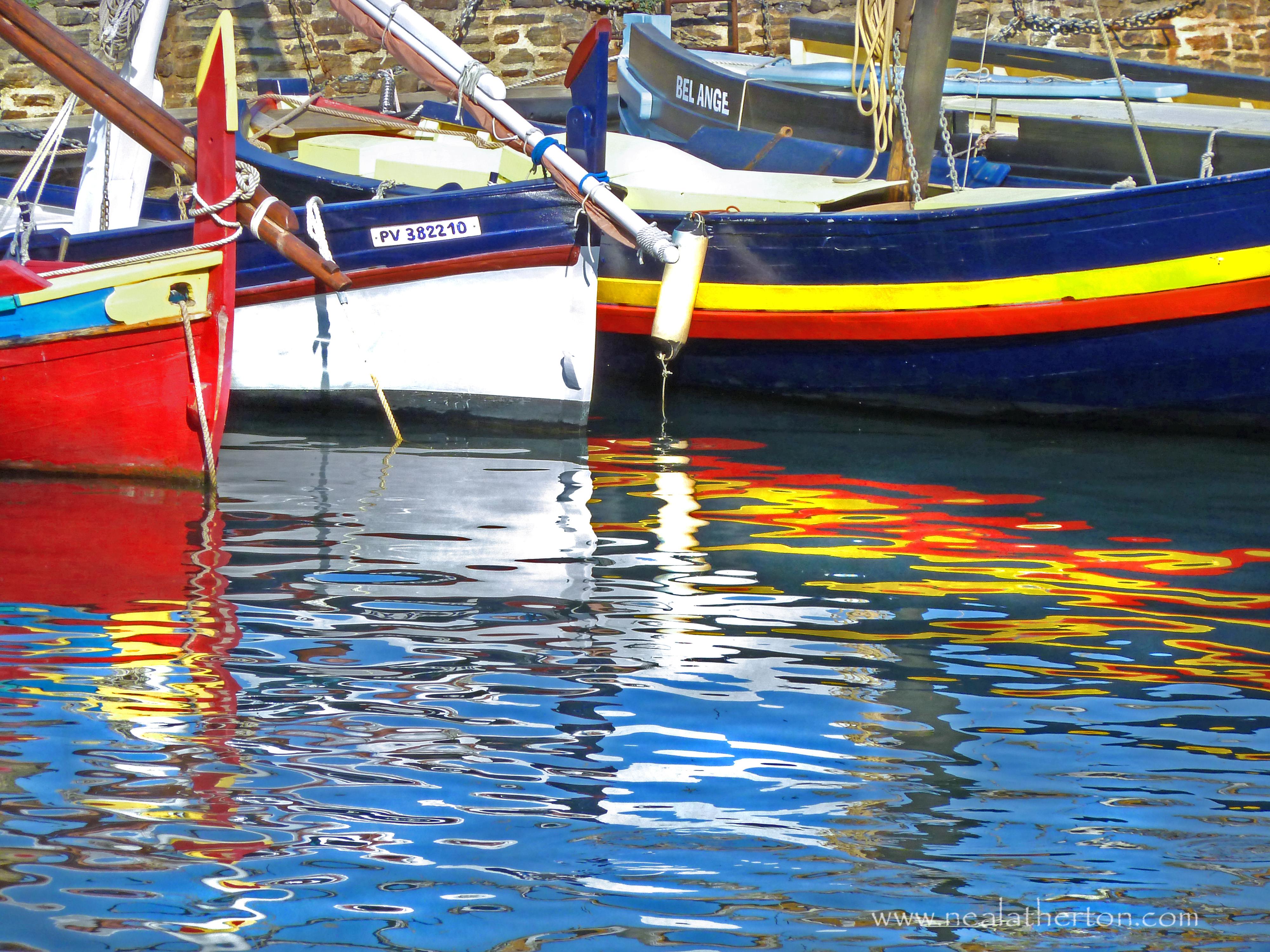 Brightly painted fishing boats in tranquil harbour and reflections