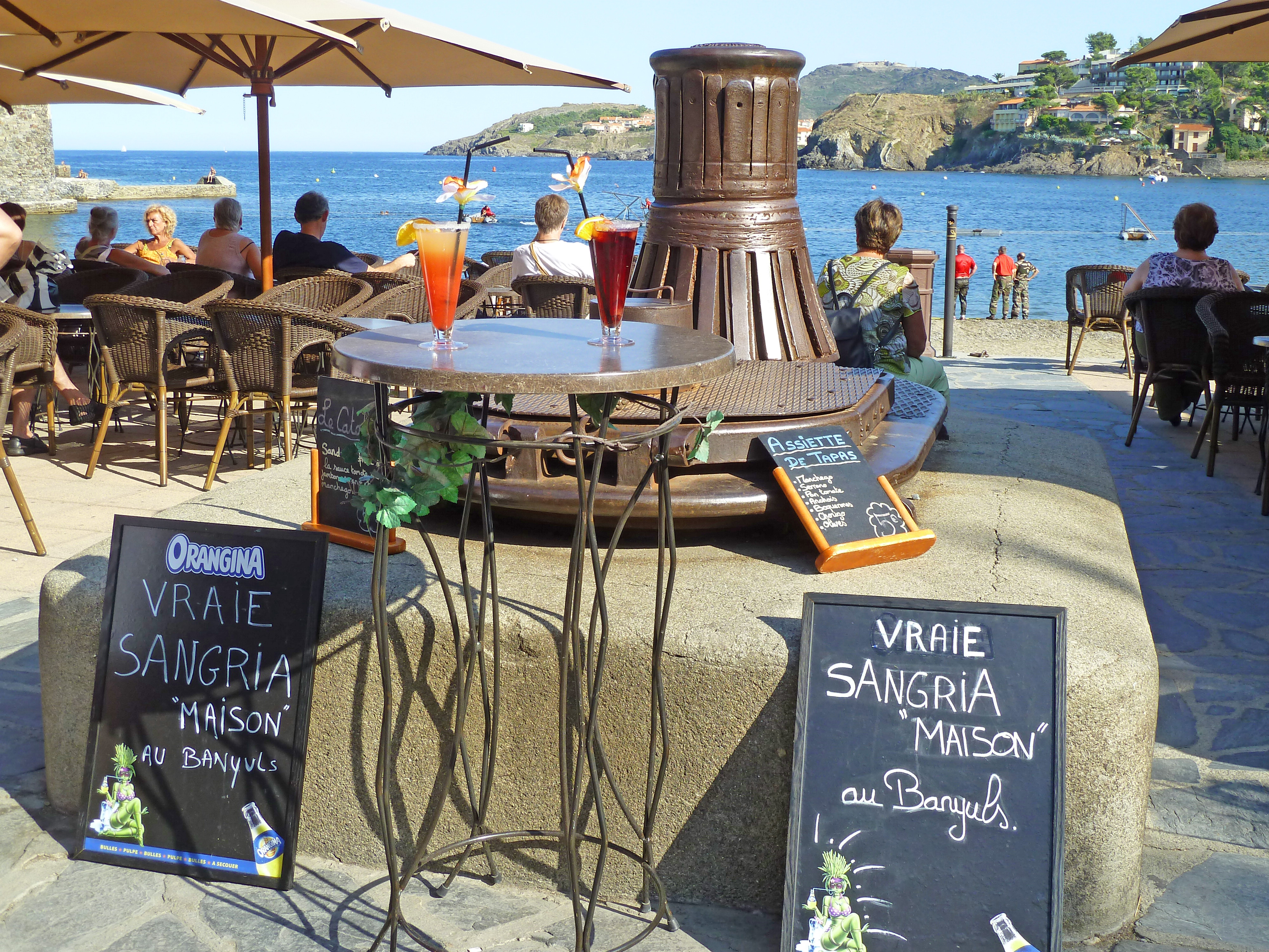 cafe signs and tables with drinks and people sitting in front of beach
