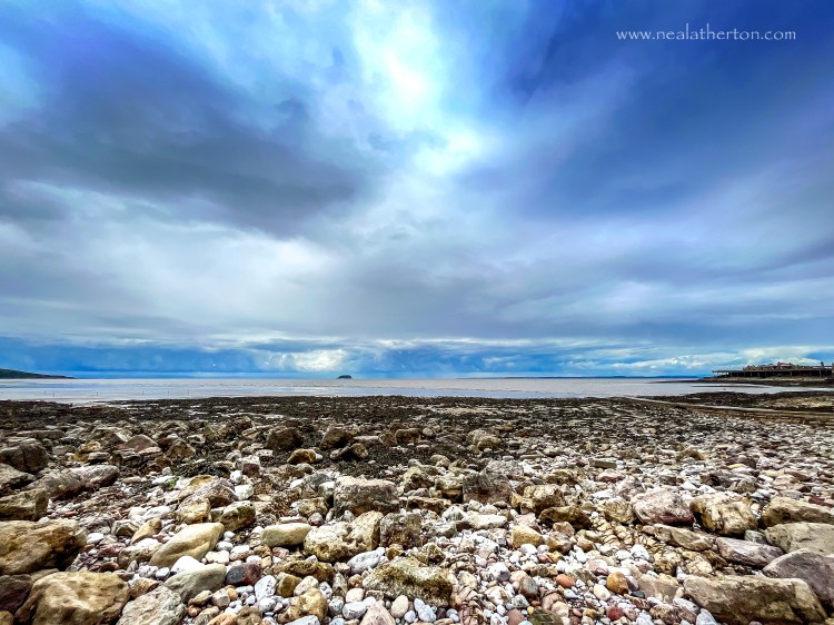 cobbles on the seashore with steep holm island in the distance and brean down on the left with Boirnbeck pier on the right