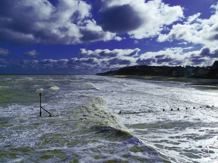 waves come in on tide to beach with surf foam and heavy winter sky