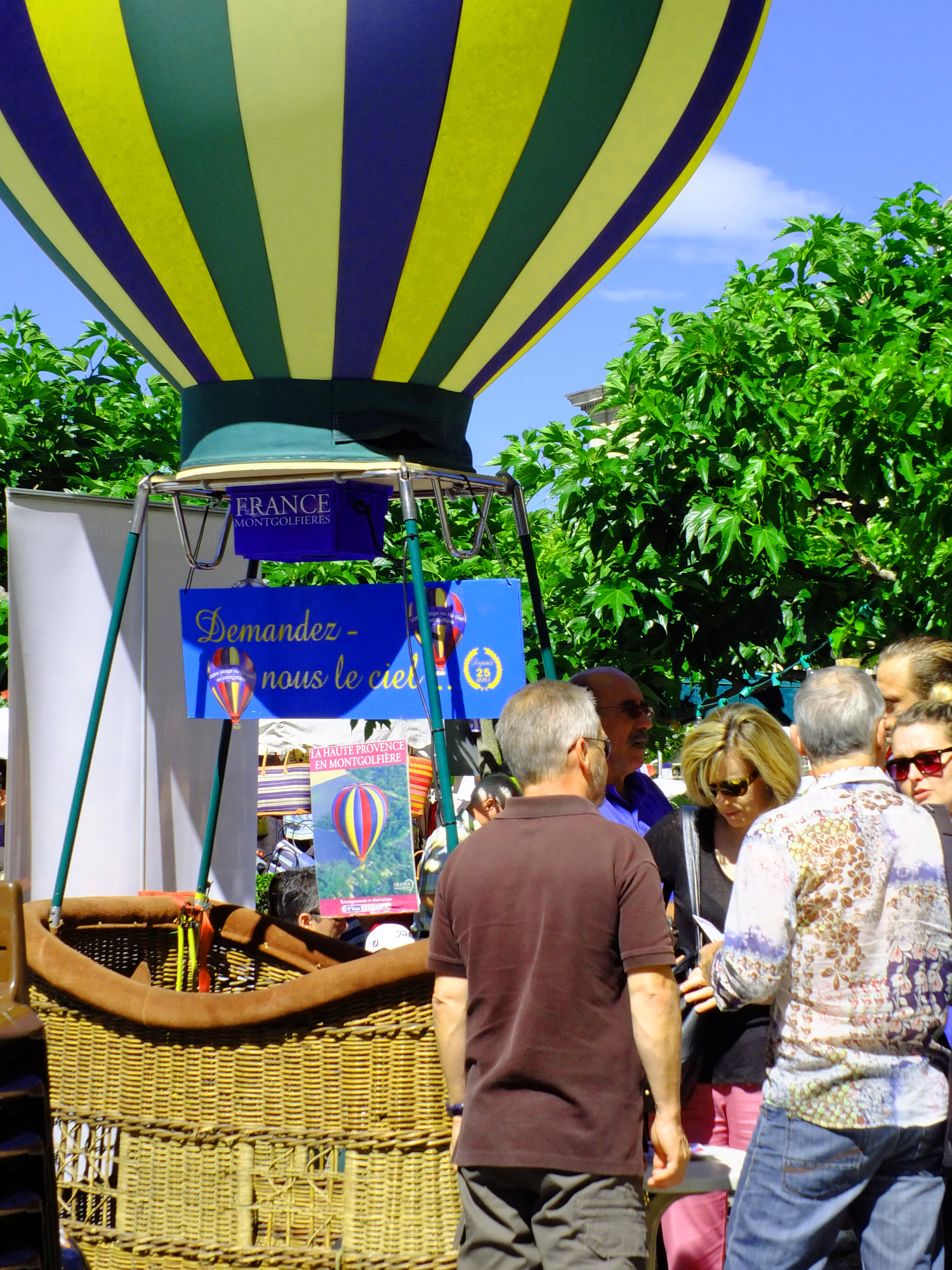 hot air balloon and basket with coloured strip balloon and people with trees