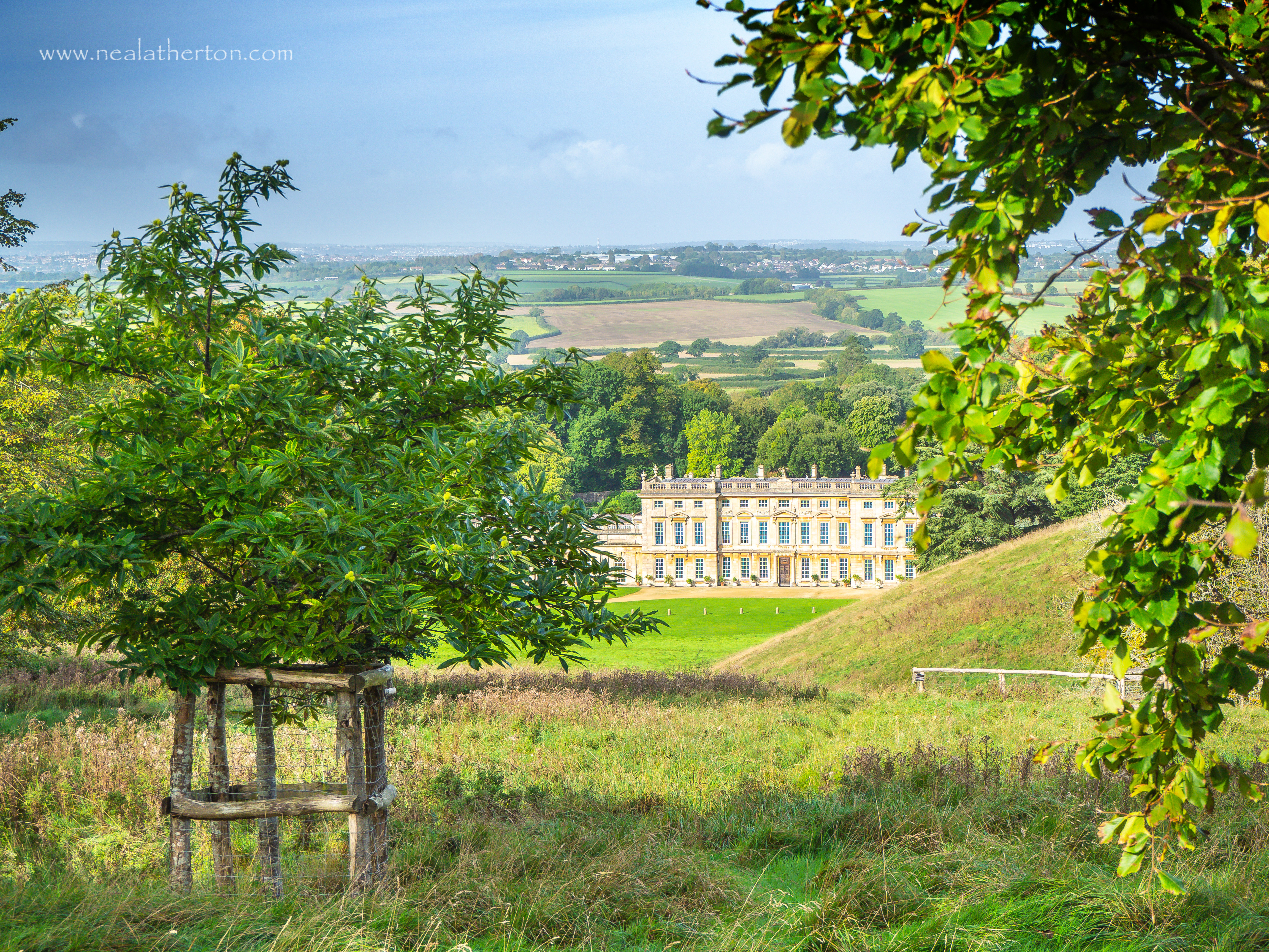 house set in valley with hills and grass with trees and bushes with fields beyond