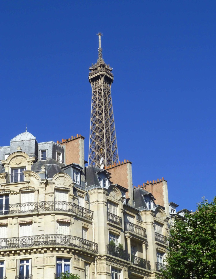 buildings and trees in from of eiffel tower and blue sky