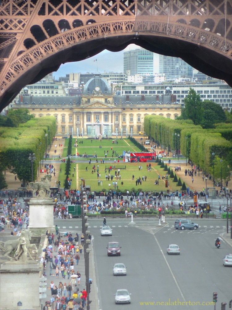 cars on road under eiffel tower with crowds of people and invalides building