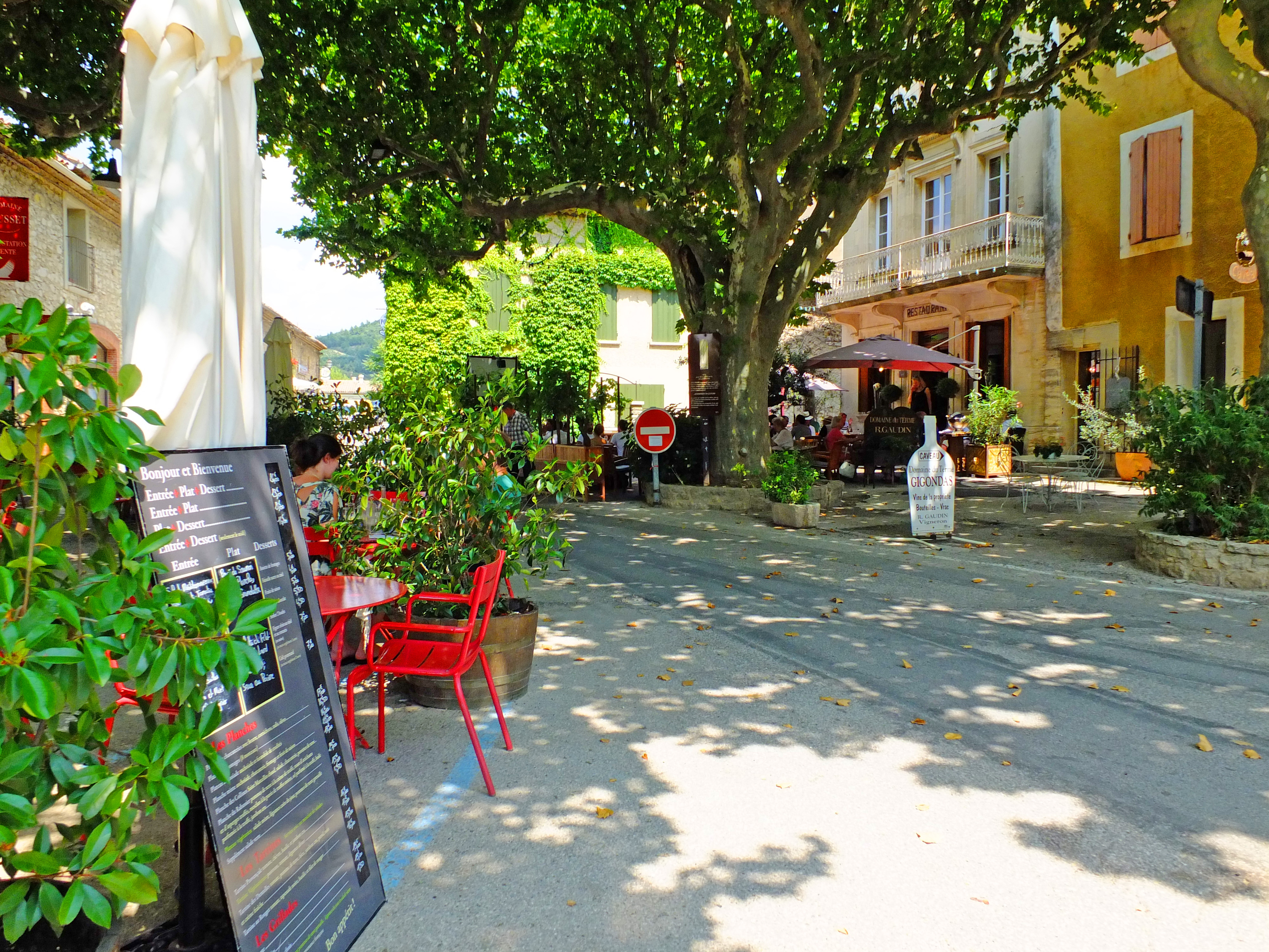 restaurant sign and parasol with street with buildings and large plane tree