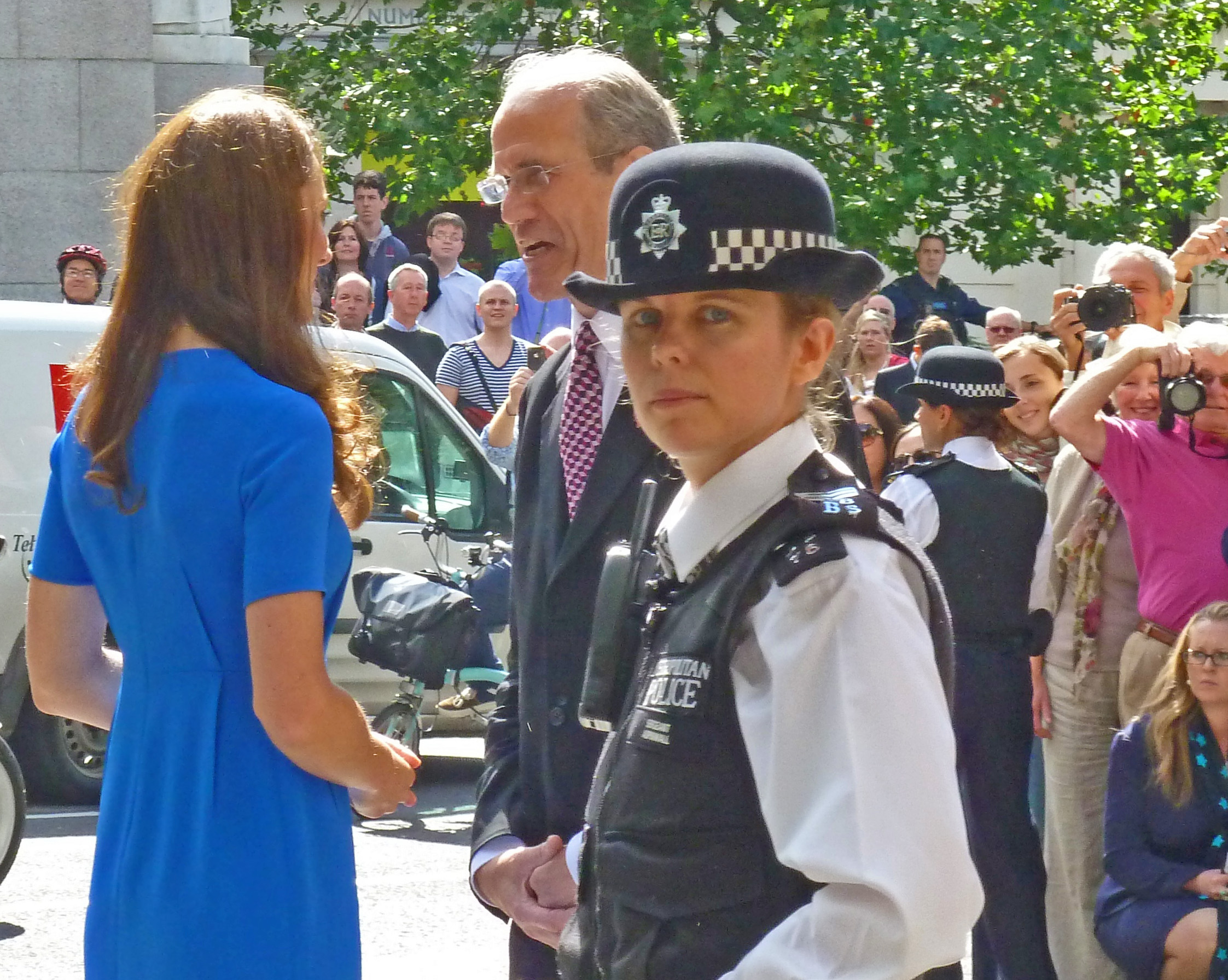 policewoman staring with Princess of Wales talking to man with crowd watching and photographing