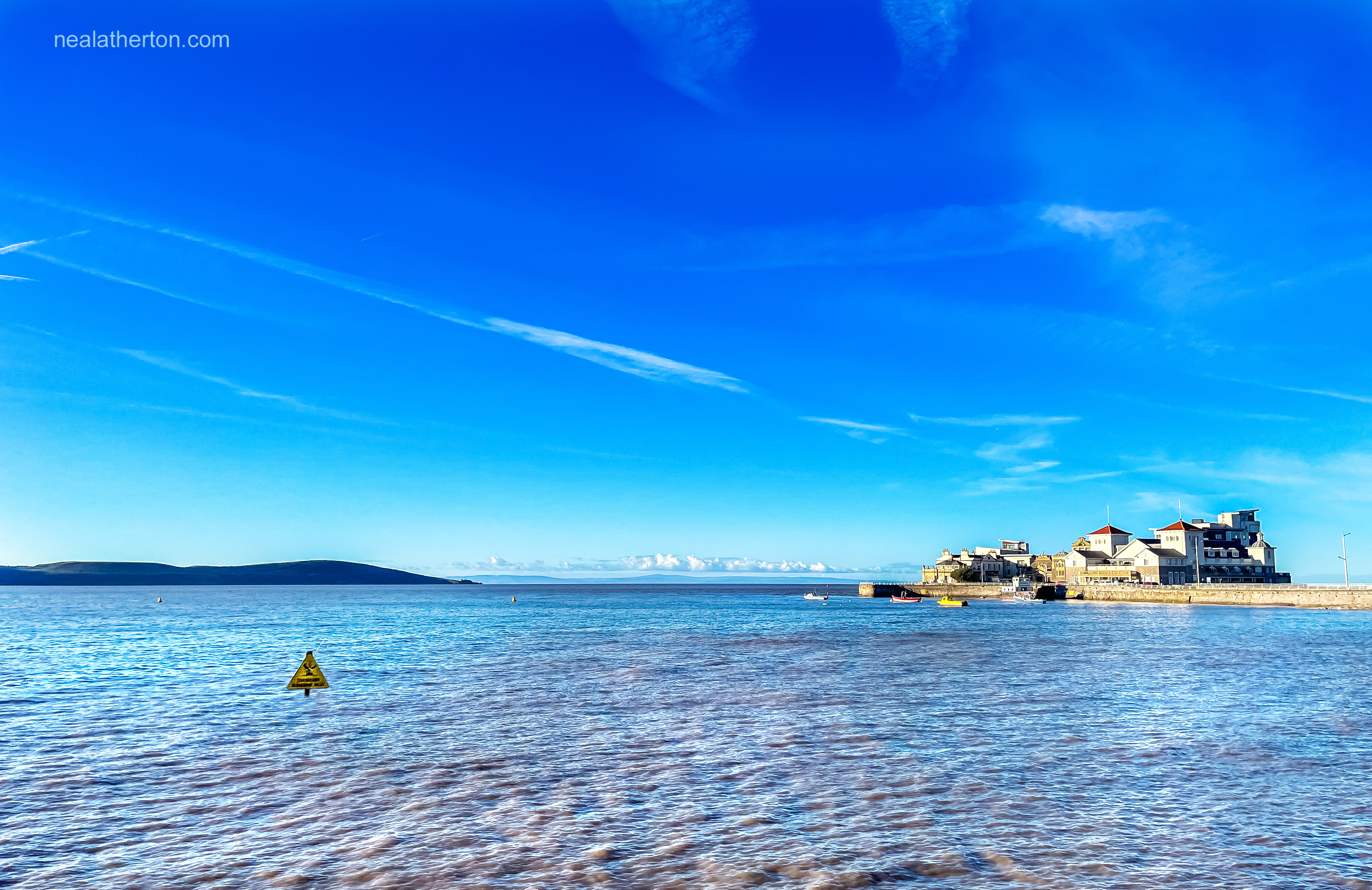 a yellow sign nearly sunberged in Weston Bay at a high tide beneath a clear blue winter sky