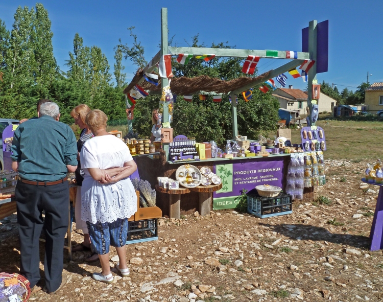 people shopping at stall selling honey and lavender with trees and houses