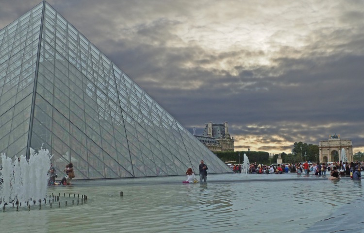 glass pyramid with pond and fountain and cloudy sky