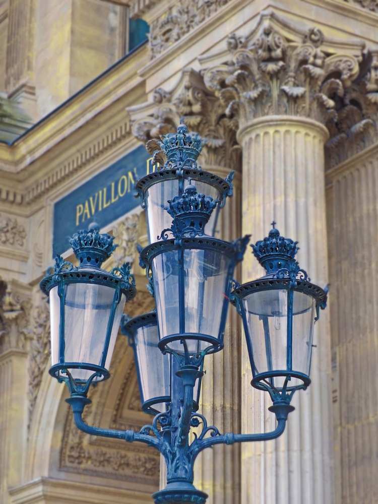 cast iron lamps with glass and finials in front of stonre columns and arch door