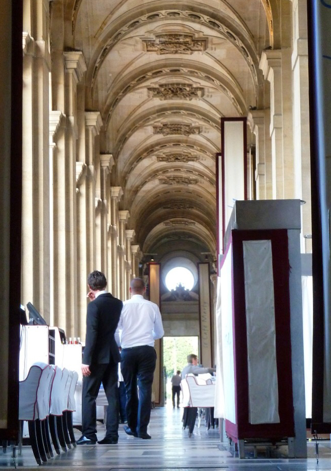 two waiters in restaurant at tables with vaulted stone roof