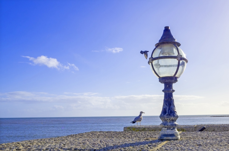 Lamp on sea wall with seagulls and sea with blue sky