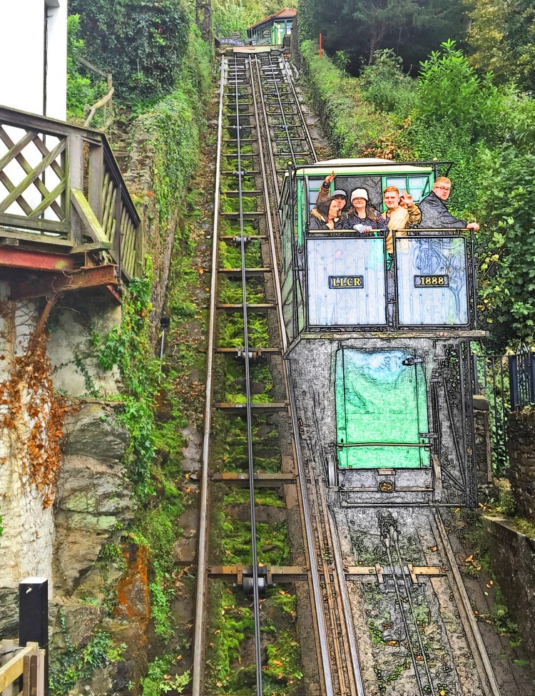 carriage on cliff railway with people inside and two tracks going up hill with house and trees