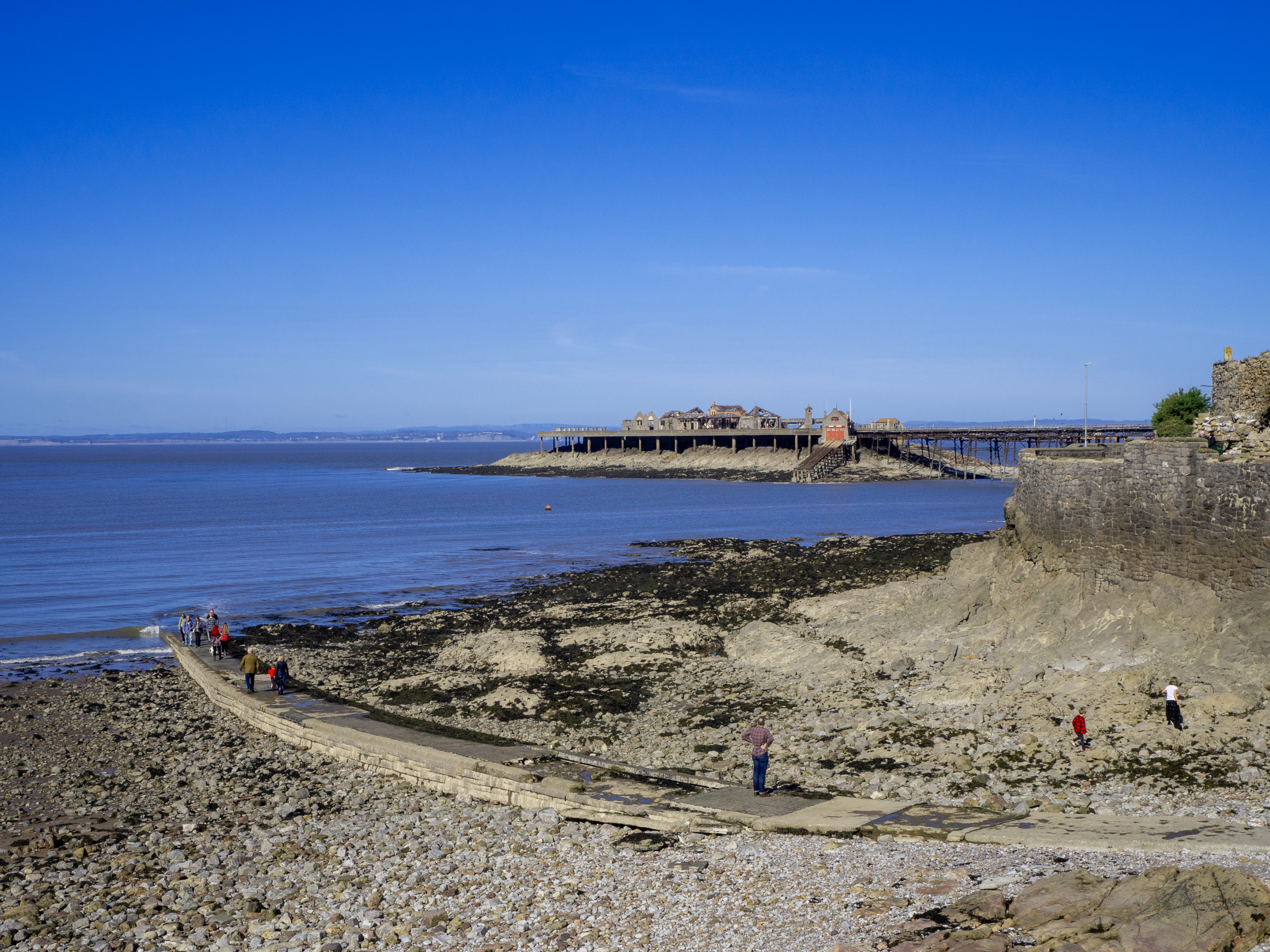 stone jetty on cobbled beach cove with old pier and sea wall by sea
