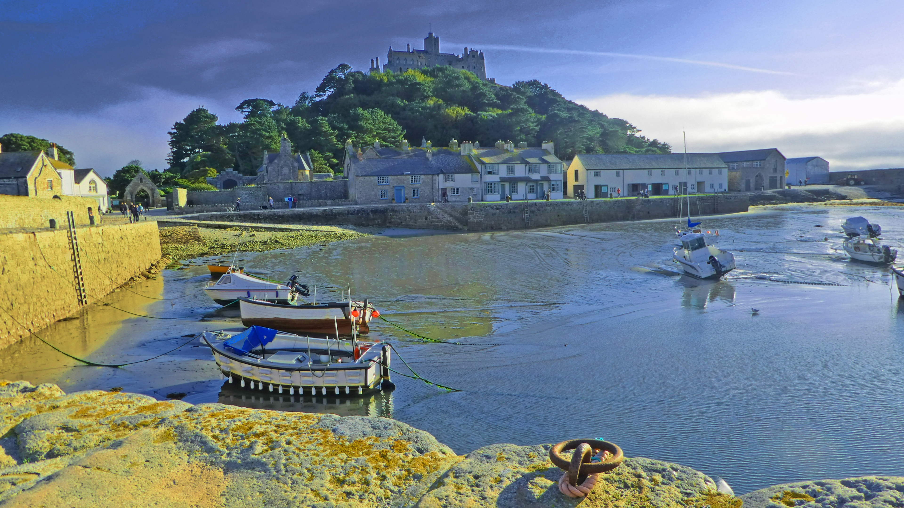 boats in harbour with stone jetty and island with castle