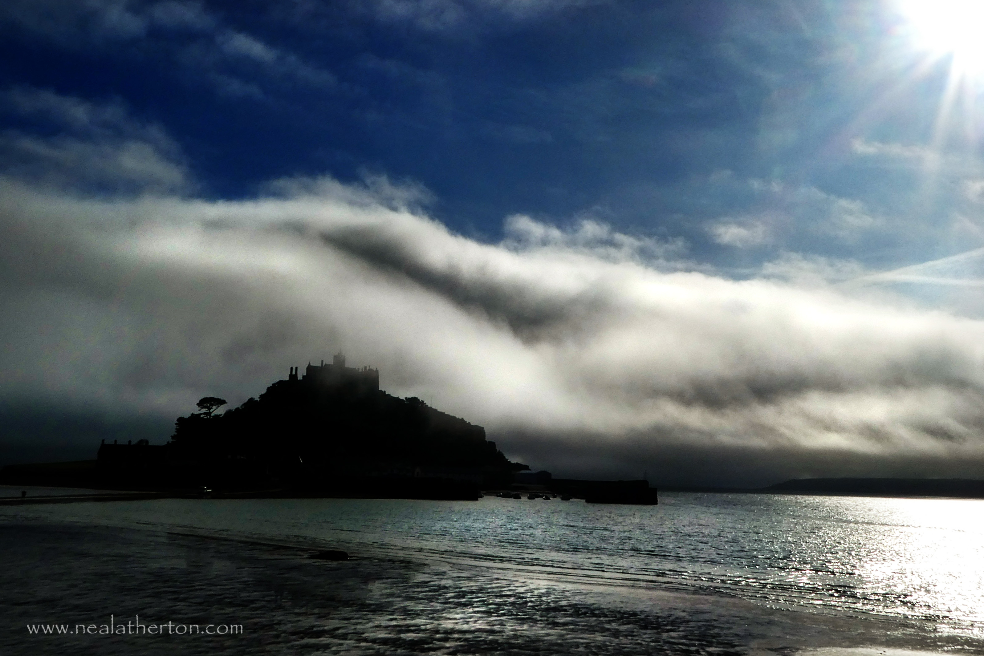 sea and island with castle with clouds rolling in from dark evening sky