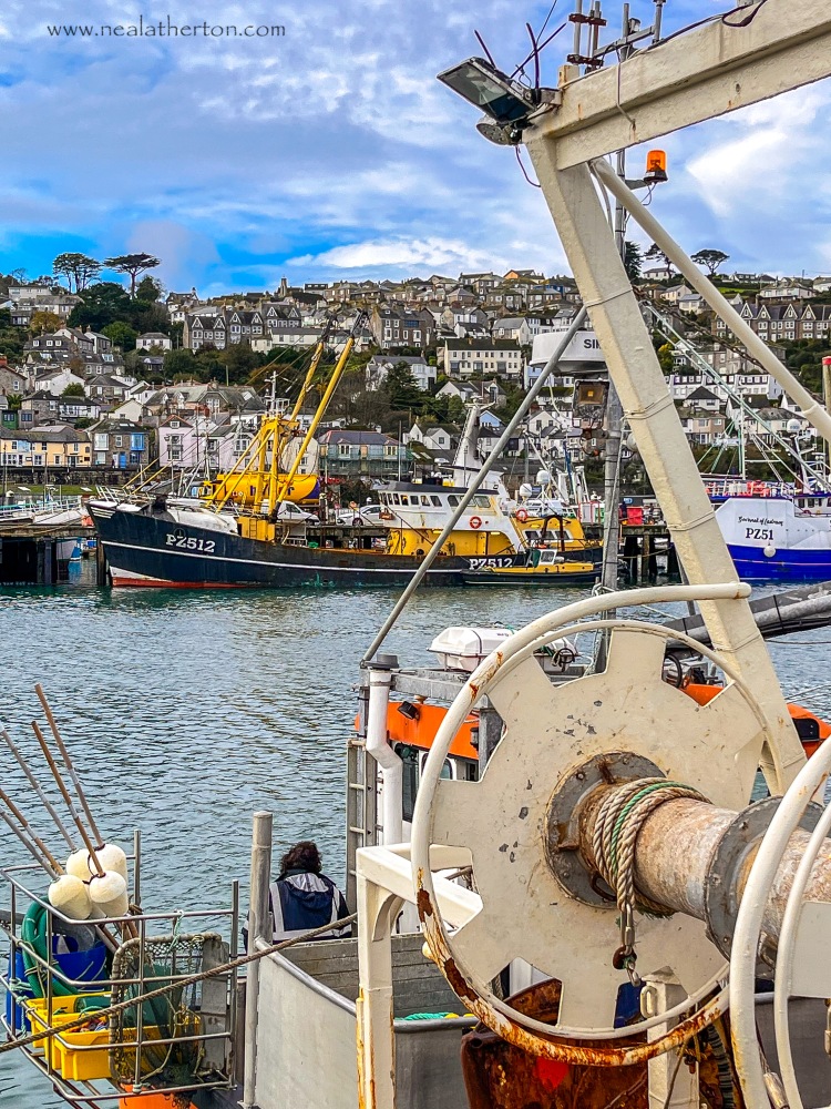 Fishing trawlers in harbour with fishing gear and town with unsettled sky