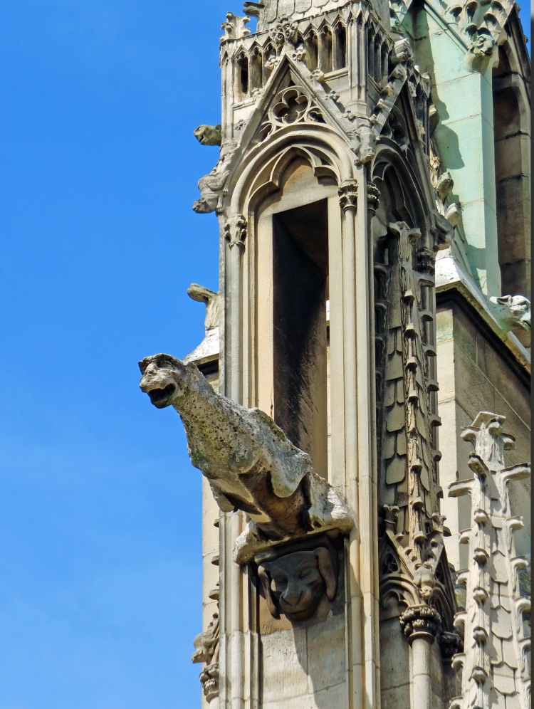 stone gargoyle statue on side of cathdral tower with blue sky