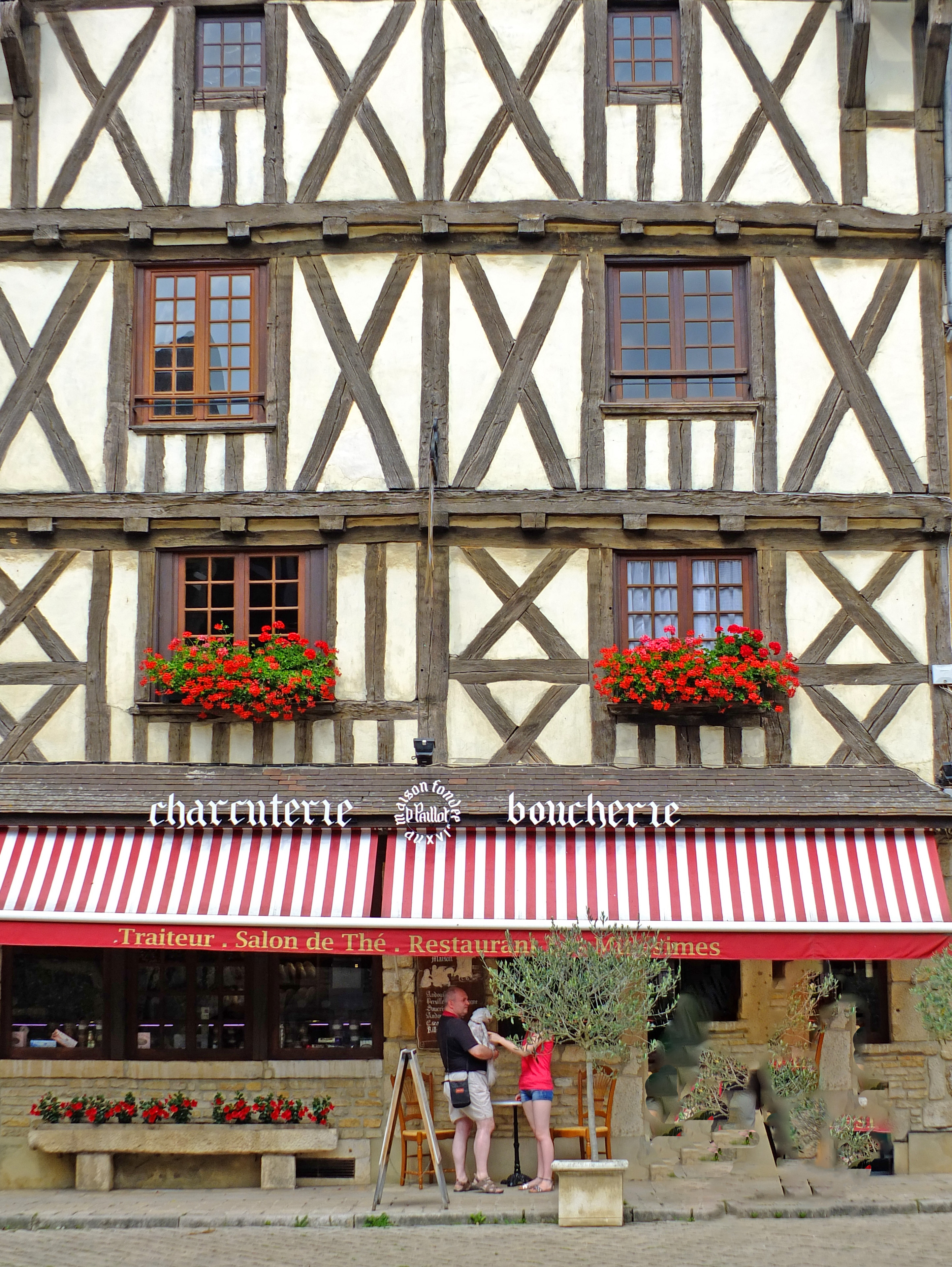 Two people look in shop wind in timber fronted house in medieval village