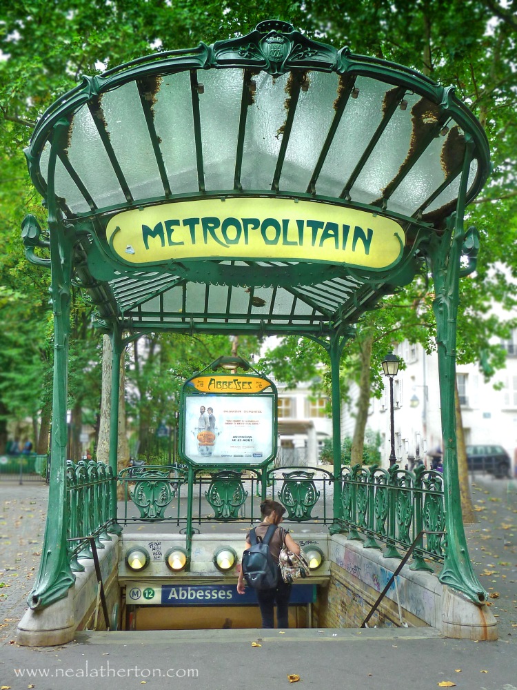 entrance to underground train station with metal and glass archway in green and metro sign