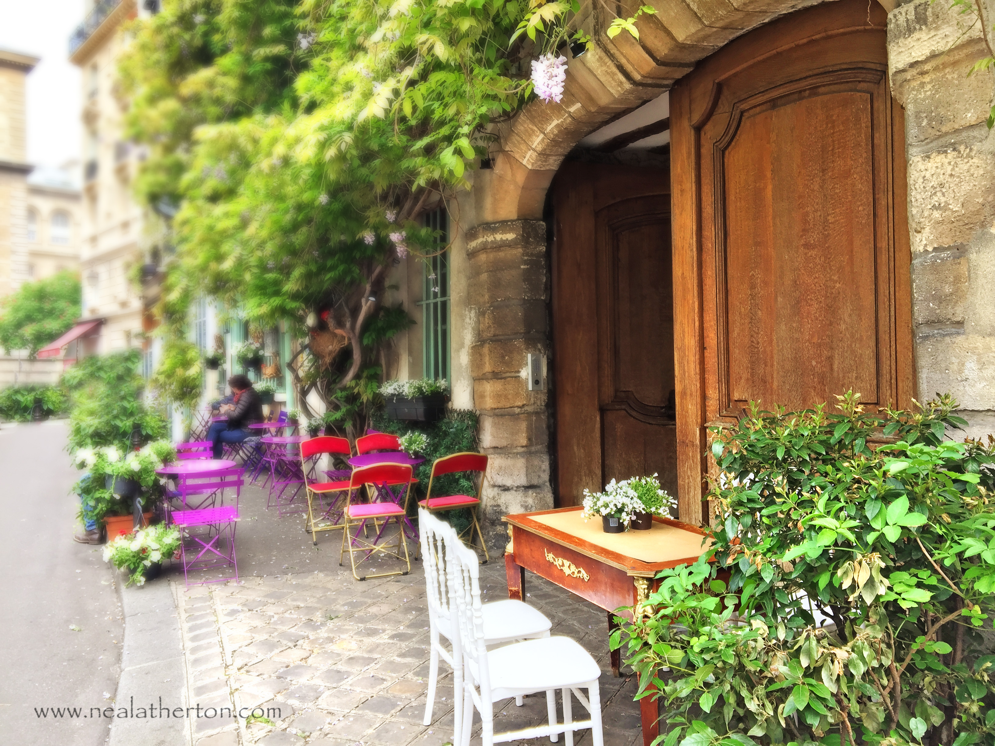 antique table by wooden doors in archway with trees and cobbled street