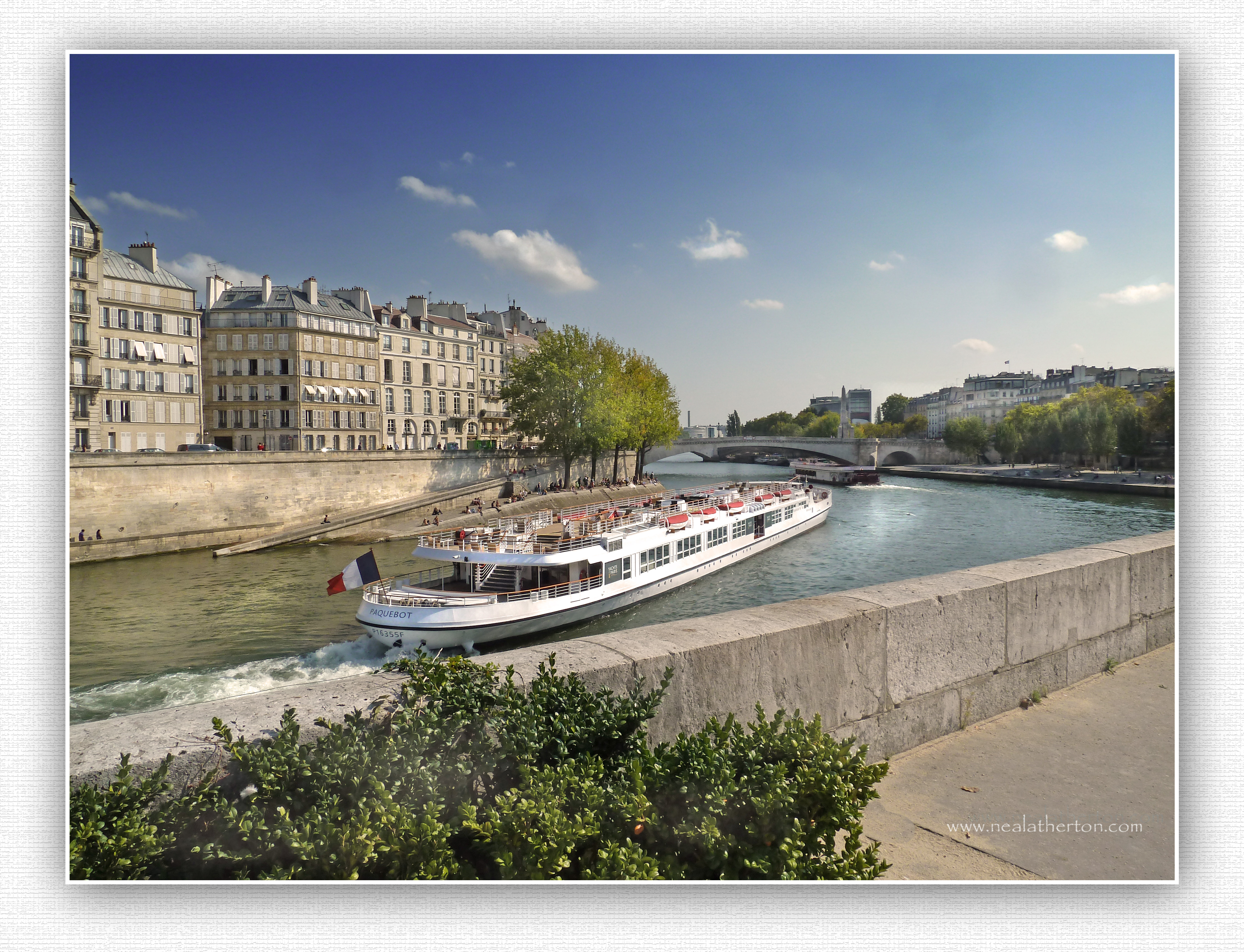large boat on river by bridge with building on quayside