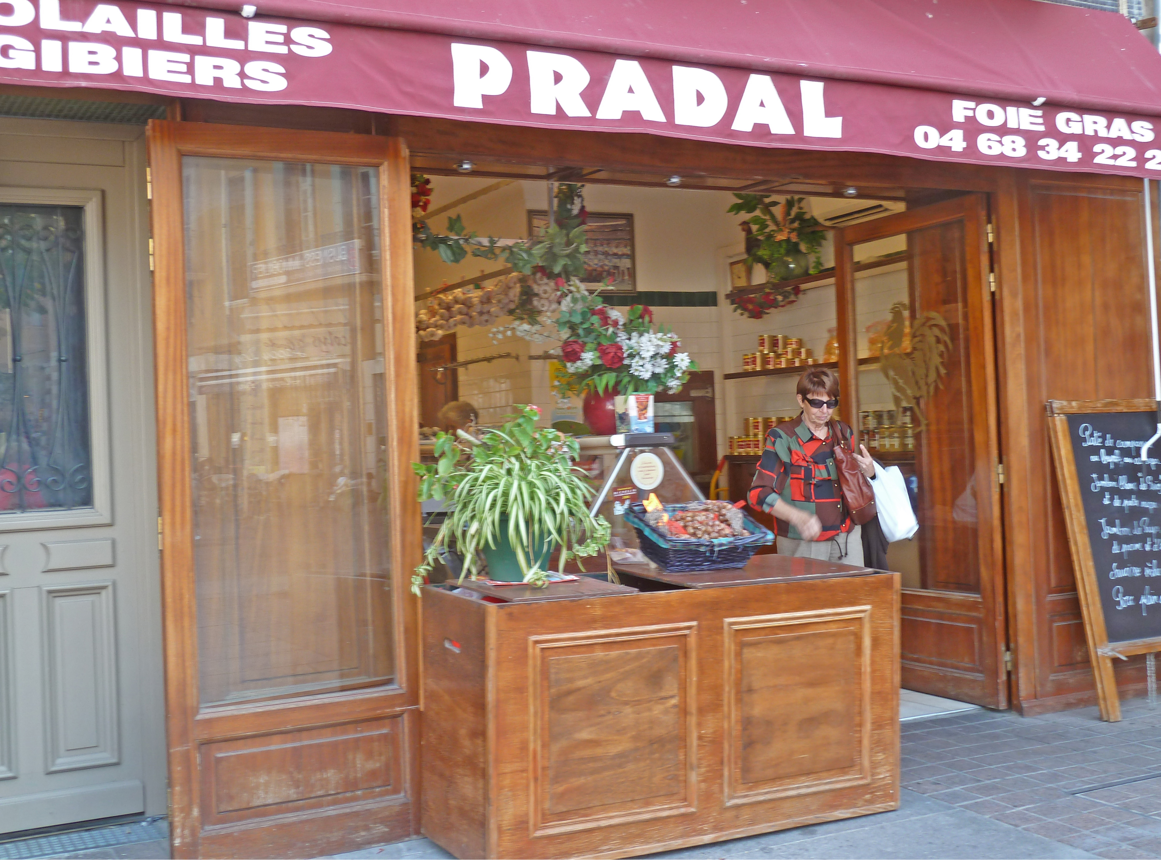 Lady shopping in wooden fronted shop with menu board