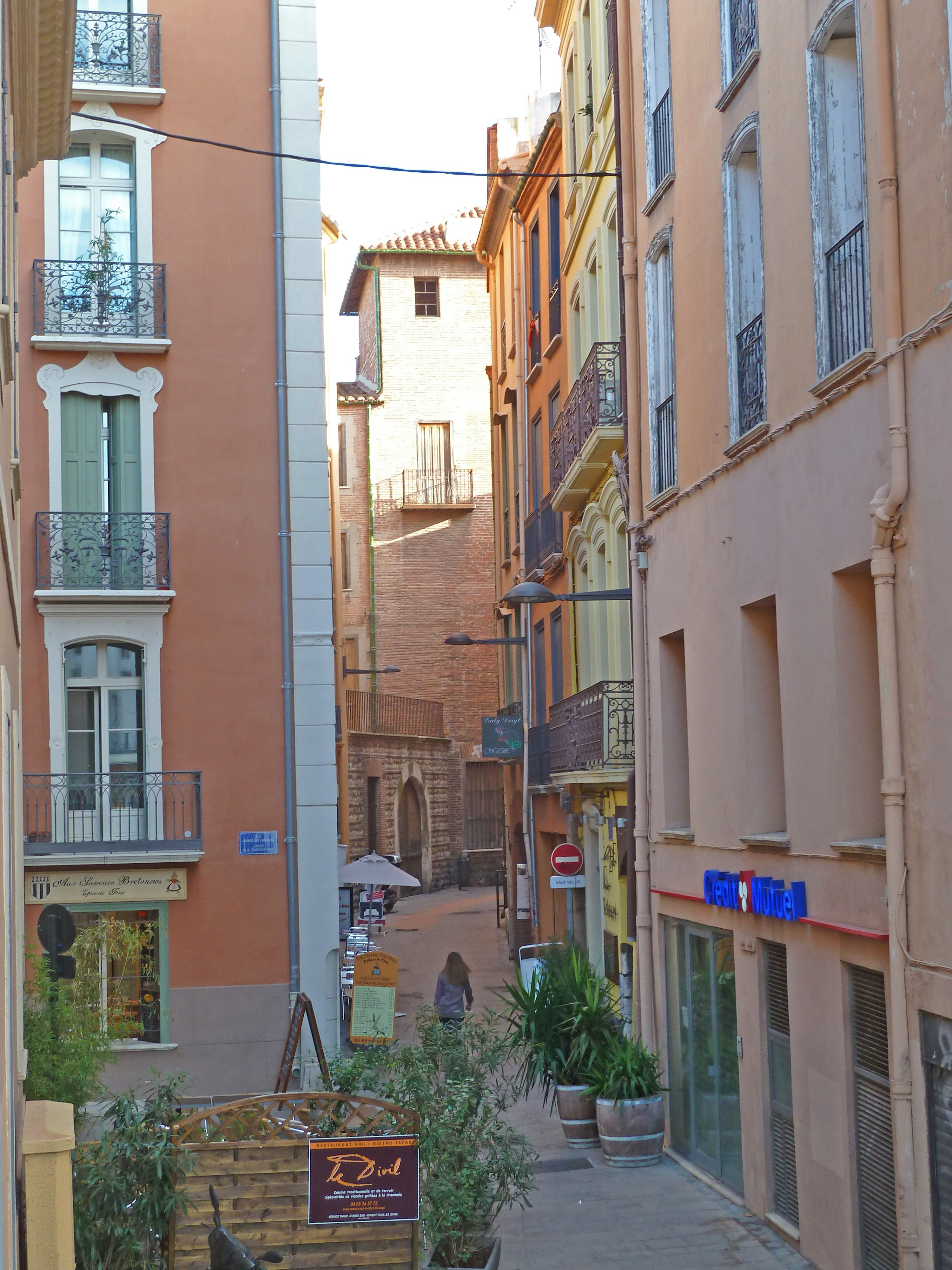 narrow street with buildings with balcony and girl walking