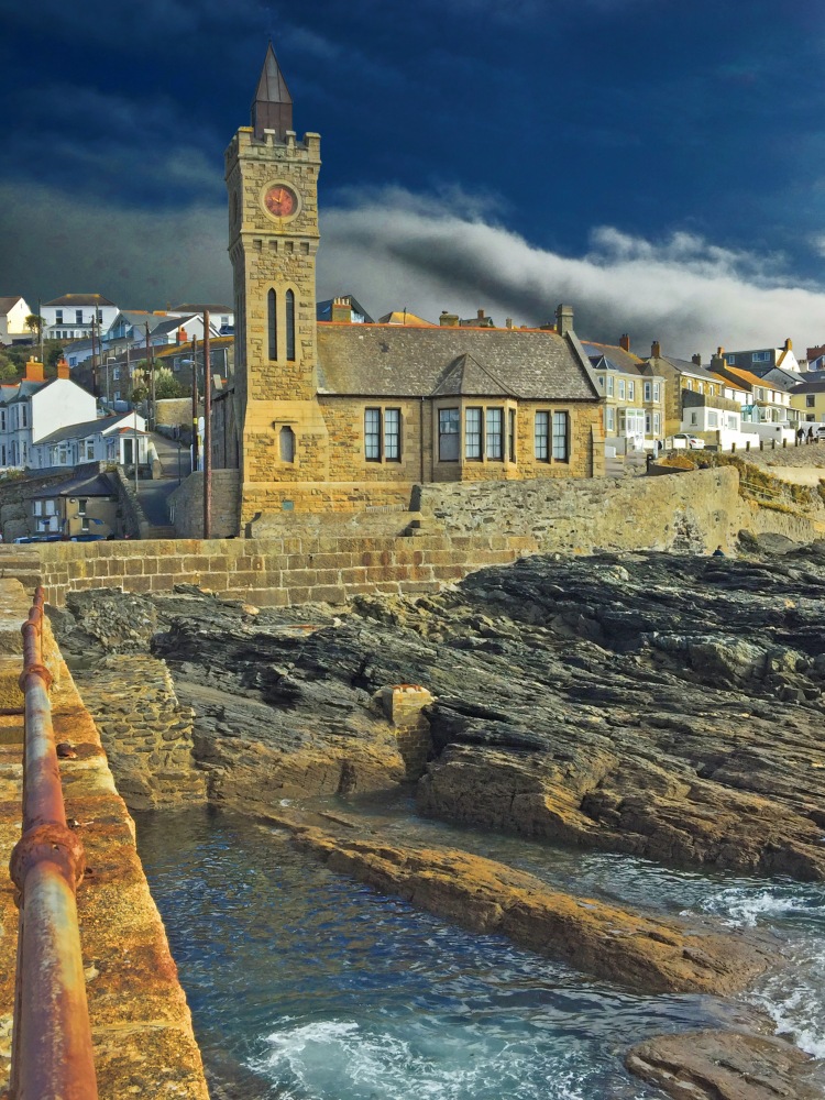 clock tower building on pier and rocks with sea and stormy sky