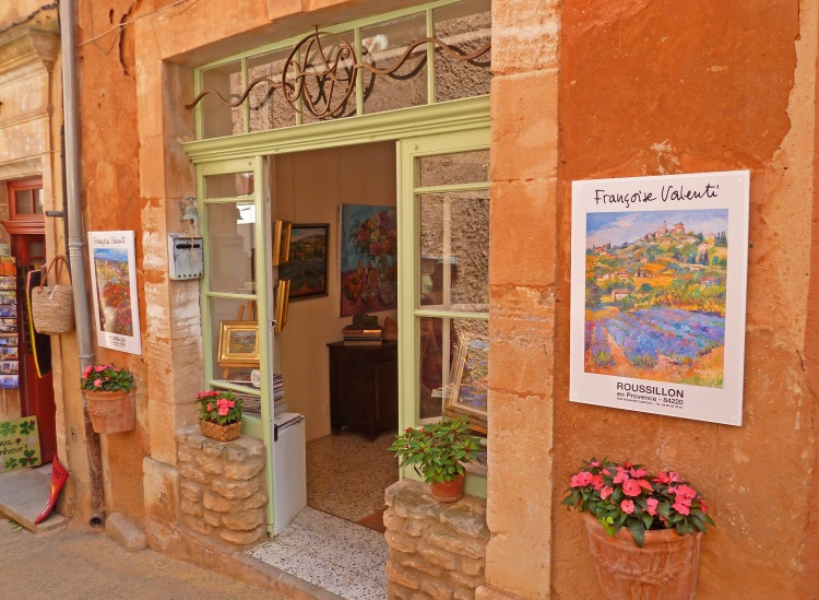 Artwork in window of village studio with plants and interior view