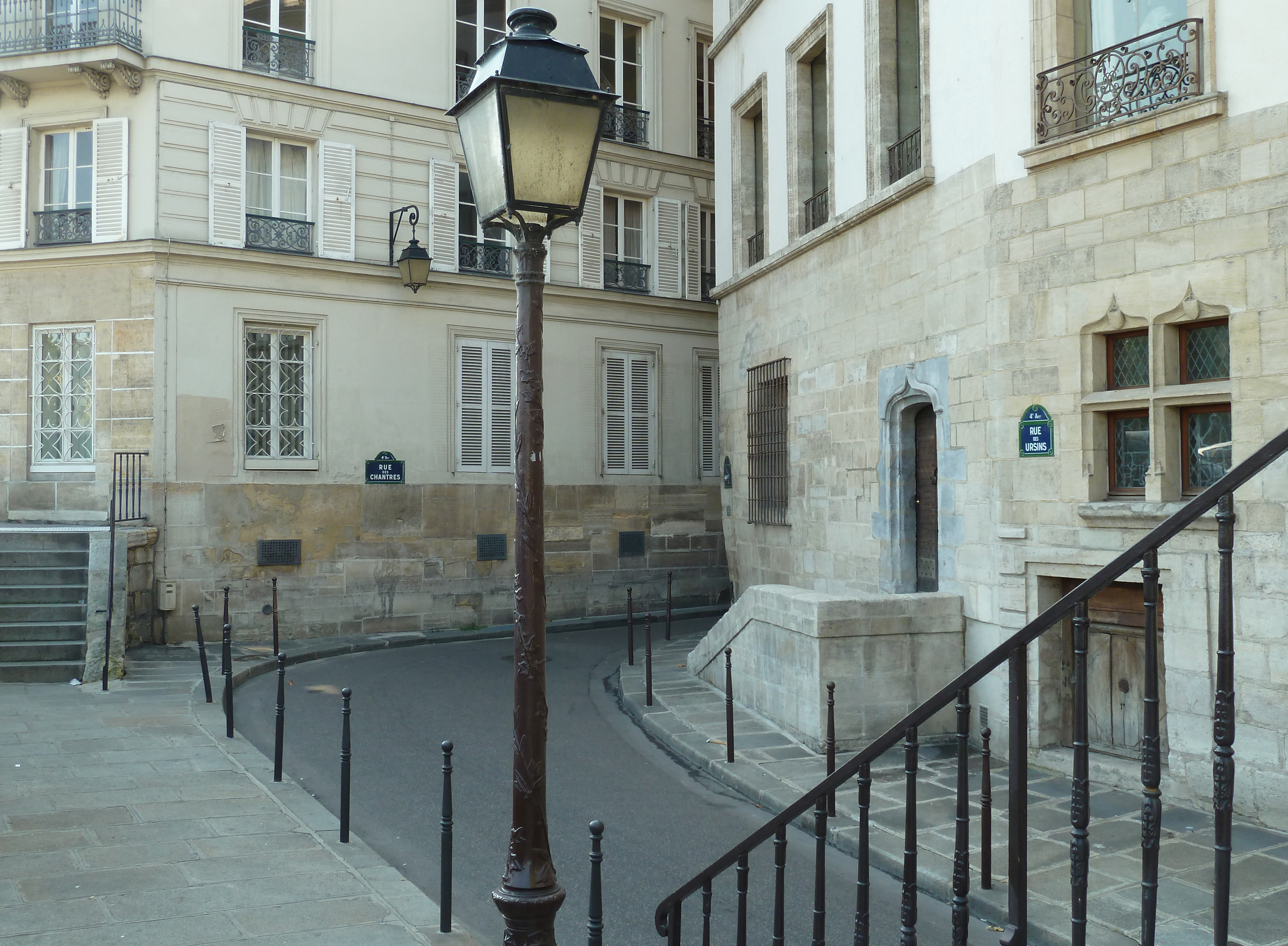 old lampost and iron railings with steps on old street in city with stone buildings
