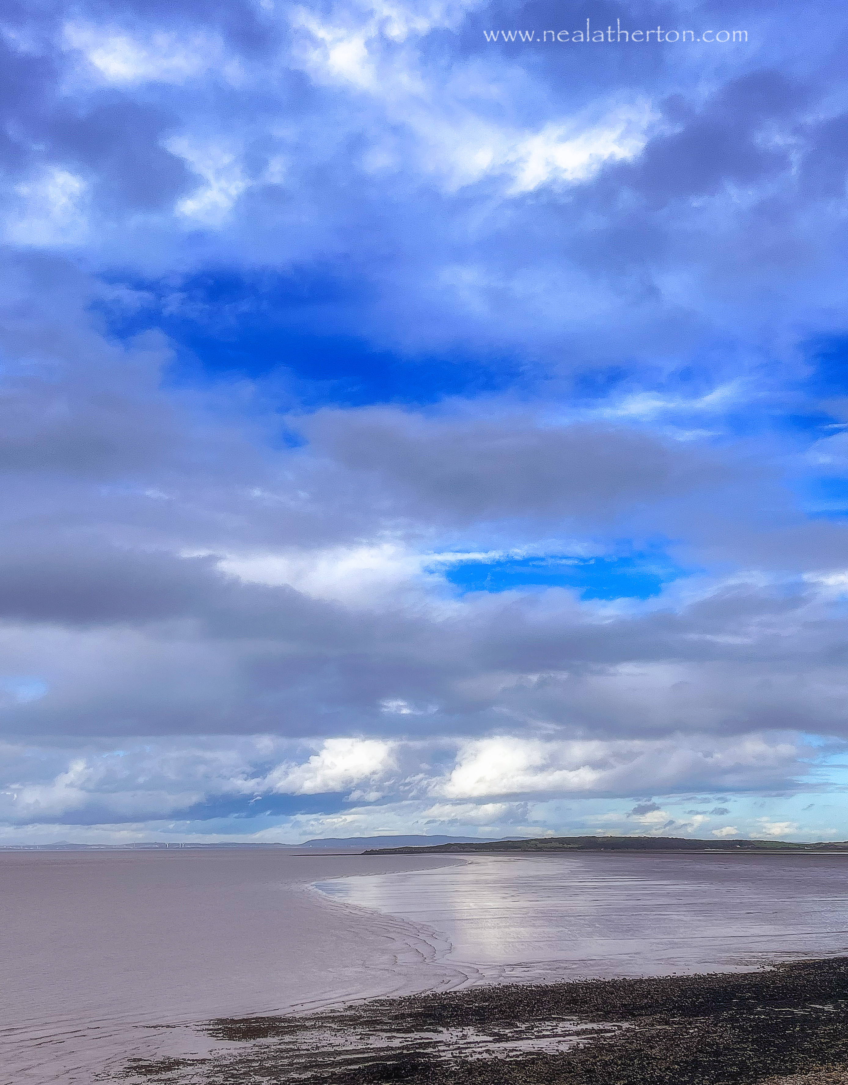 Bay with incoming tide and sea under cloudy sky